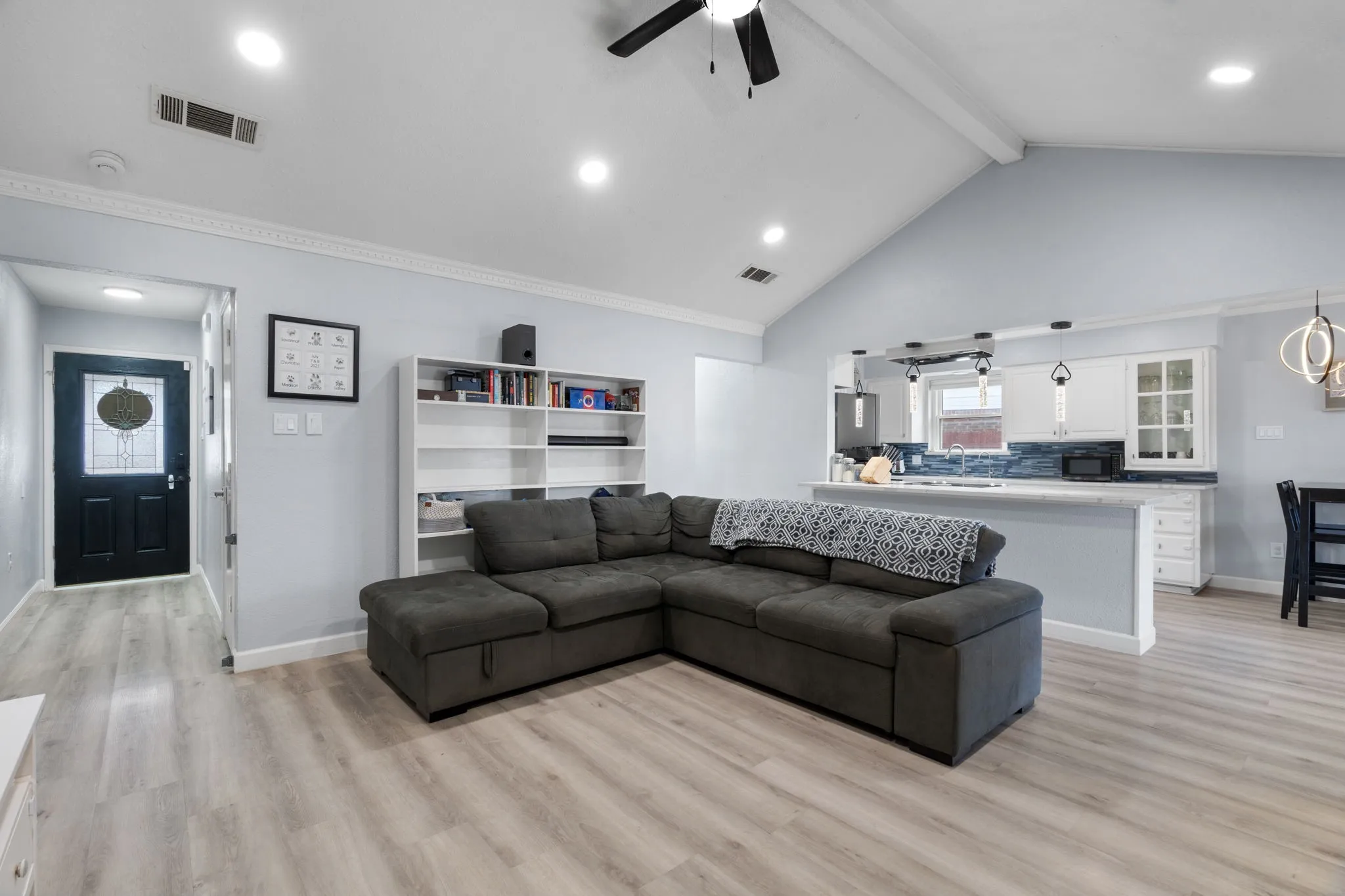Vaulted ceiling living area featuring wood-finish flooring, recessed lighting, and a ceiling fan