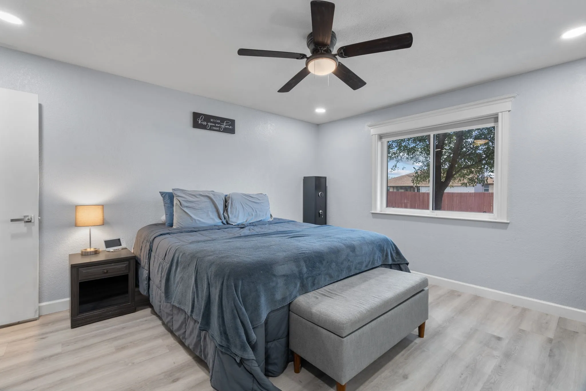 Interior room featuring light wood-finish flooring, light gray walls, and a white door with brushed nickel hardware
