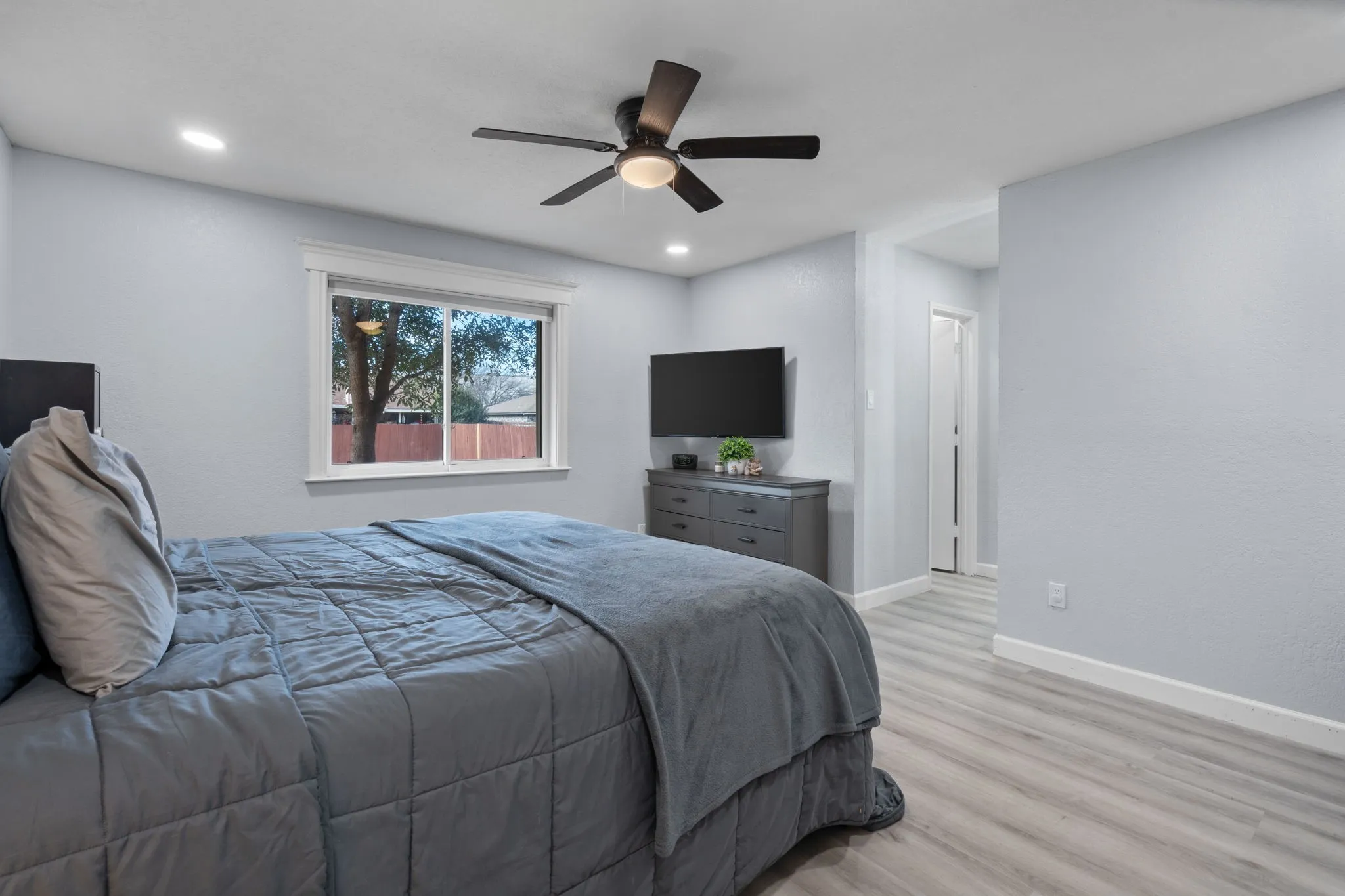 Recessed lighting, light gray walls, wood-finish flooring, and a modern ceiling fan with integrated lighting