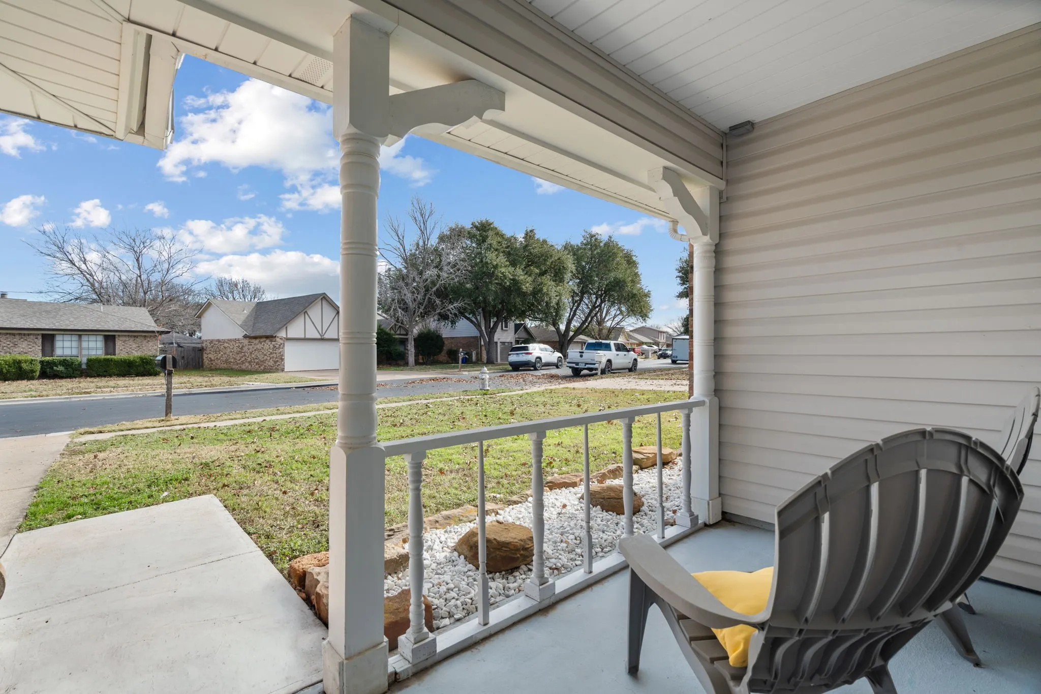 Covered front porch featuring white columns and a matching railing