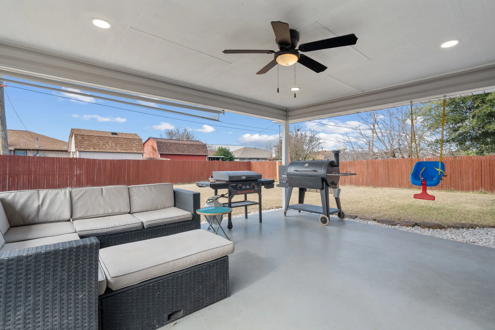 Expansive covered patio featuring a ceiling fan, recessed lighting, concrete flooring, and a gravel border