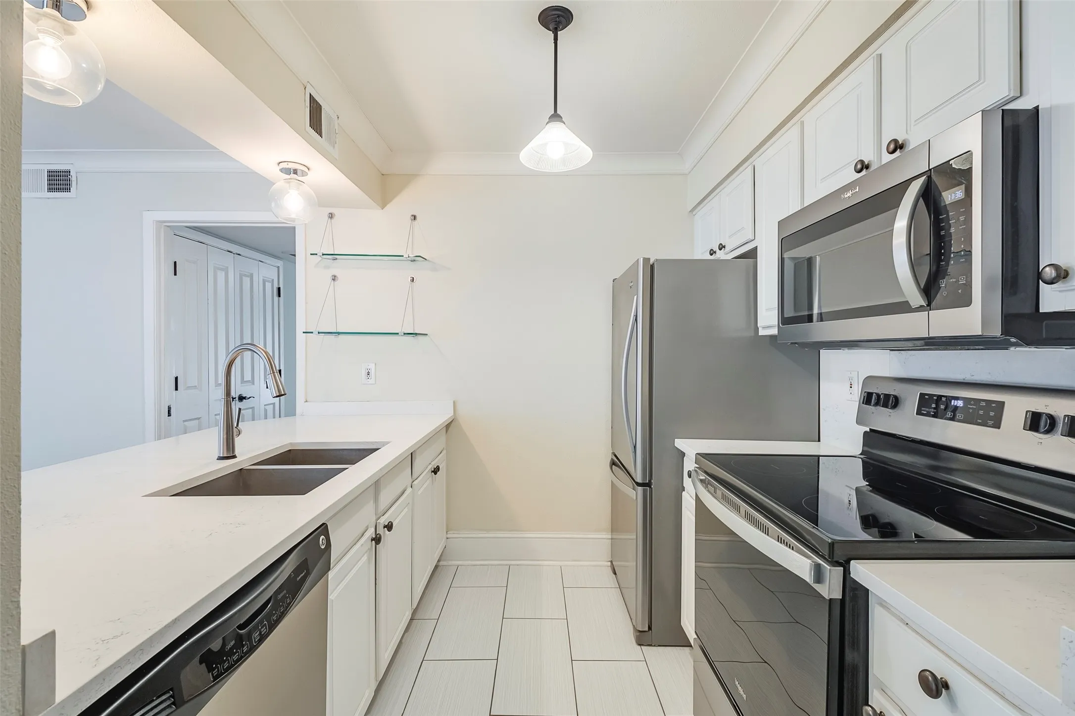 Kitchen featuring hanging light fixtures, white cabinetry, sink, and stainless steel appliances