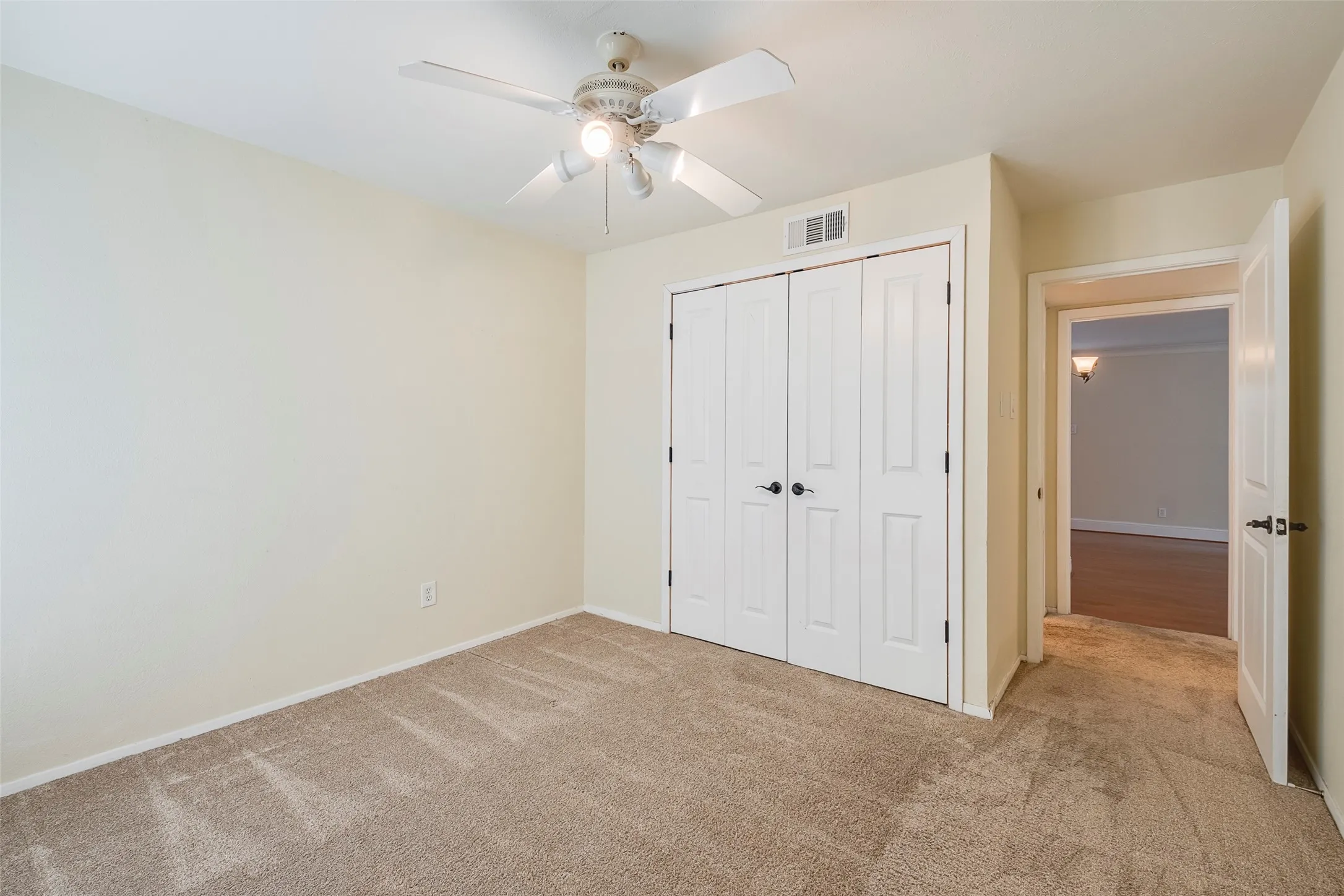 Unfurnished bedroom featuring light carpet, a closet, and ceiling fan