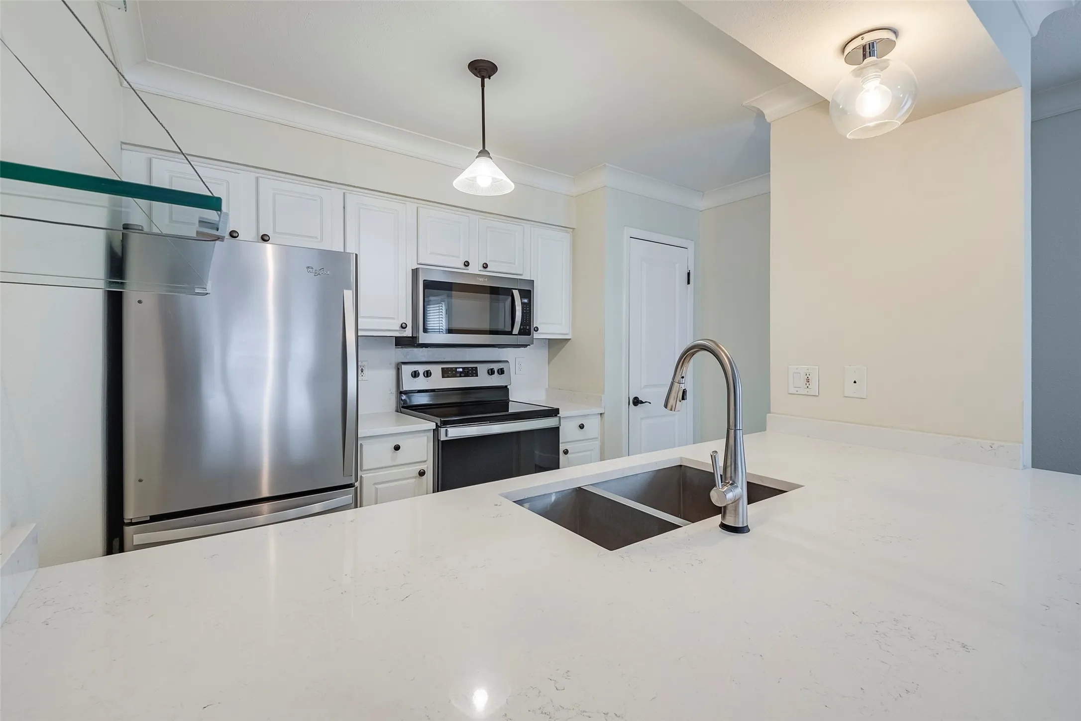 Kitchen with sink, stainless steel appliances, crown molding, decorative light fixtures, and white cabinets