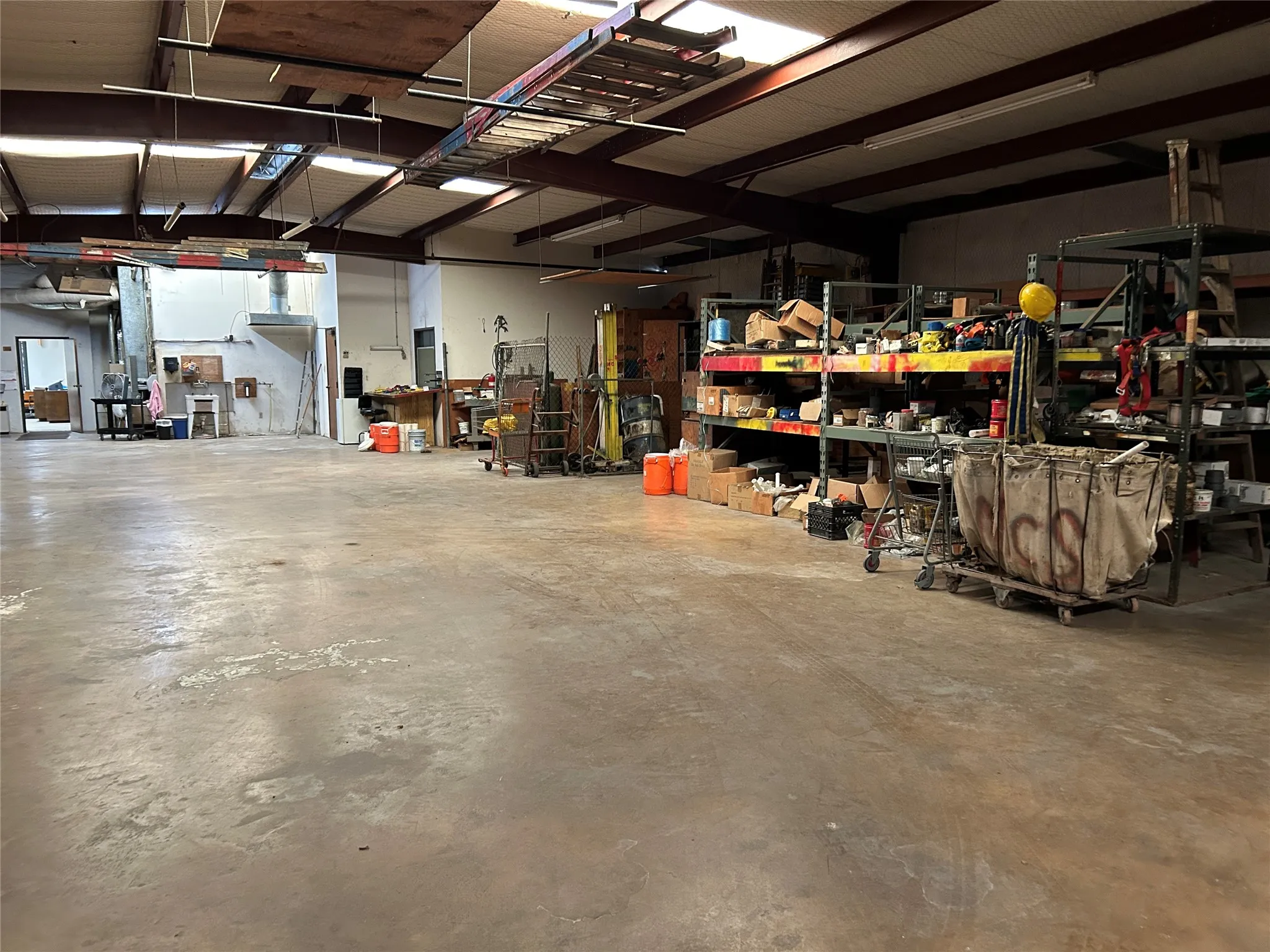 Expansive concrete flooring in a large industrial space featuring exposed metal beam ceiling construction