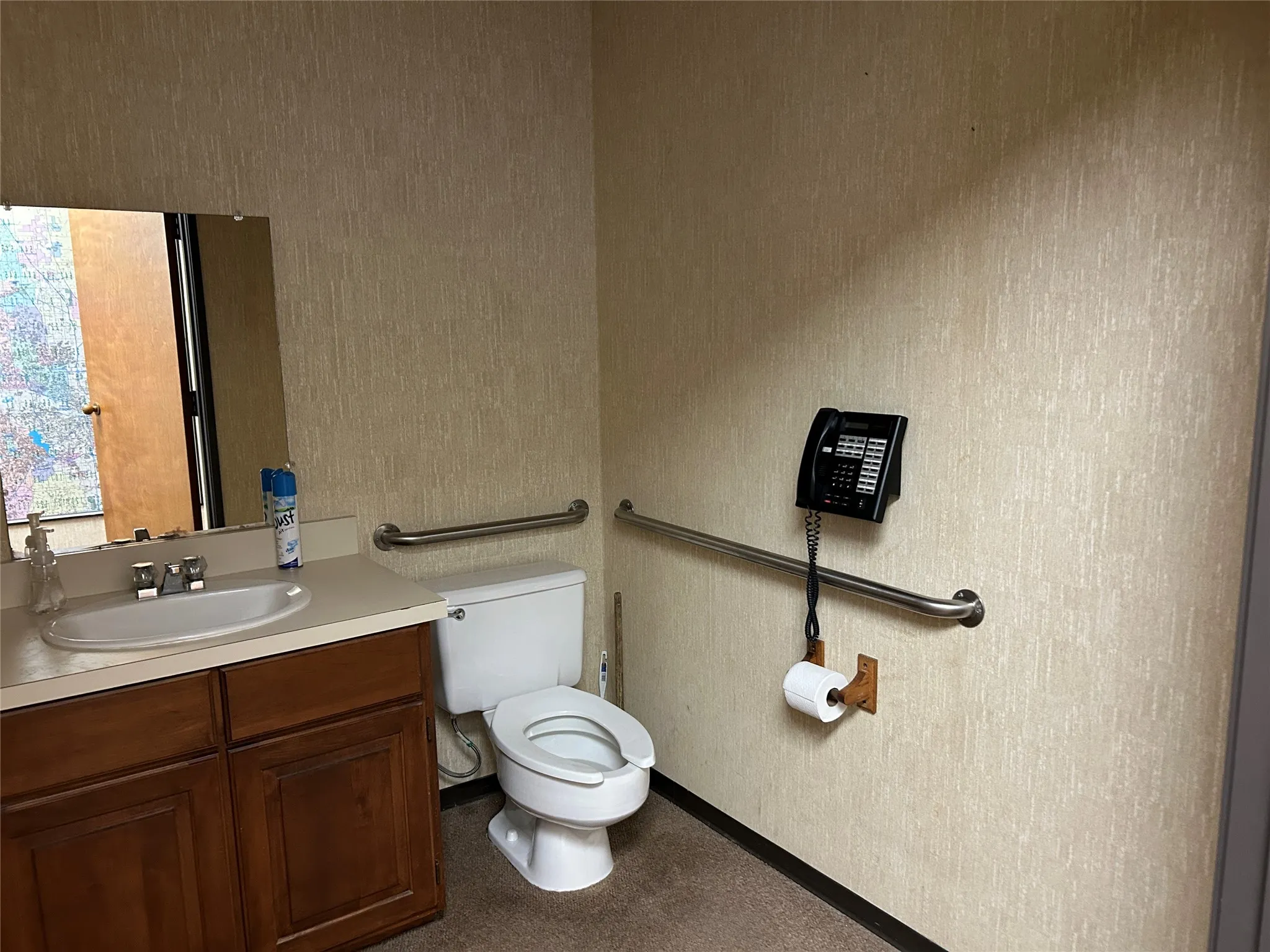 Private restroom with a single vanity, wood-finish cabinetry, and support bars