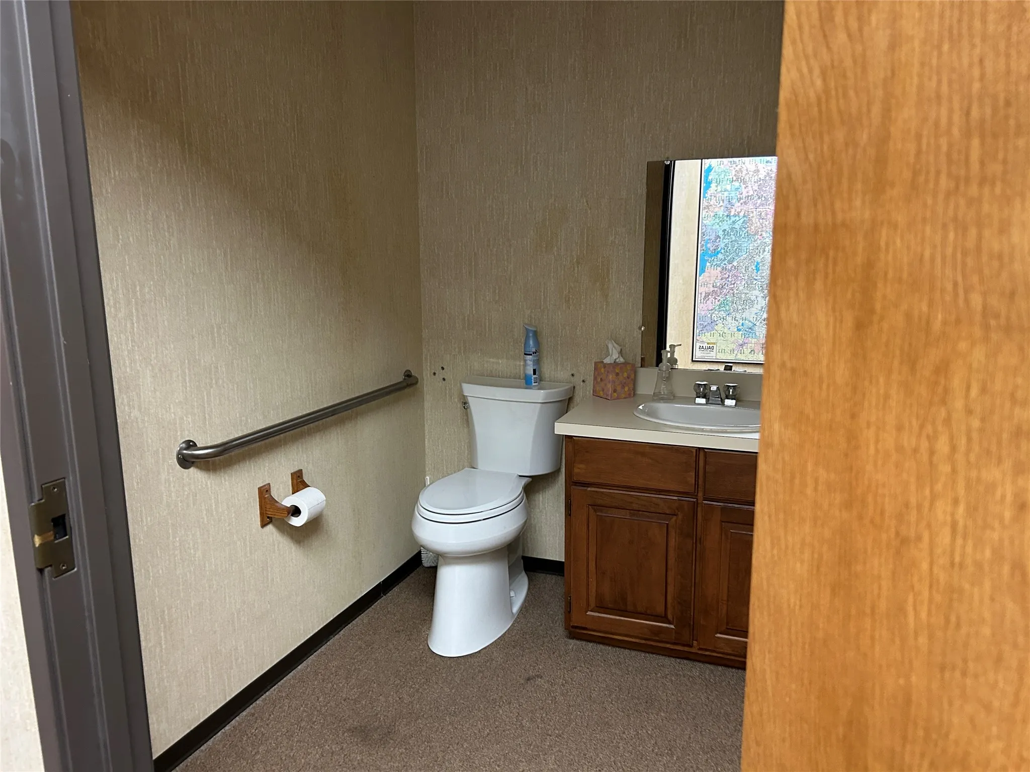 Restroom featuring a white toilet, grab bar, vanity with a white countertop, and dark wood-finish cabinetry