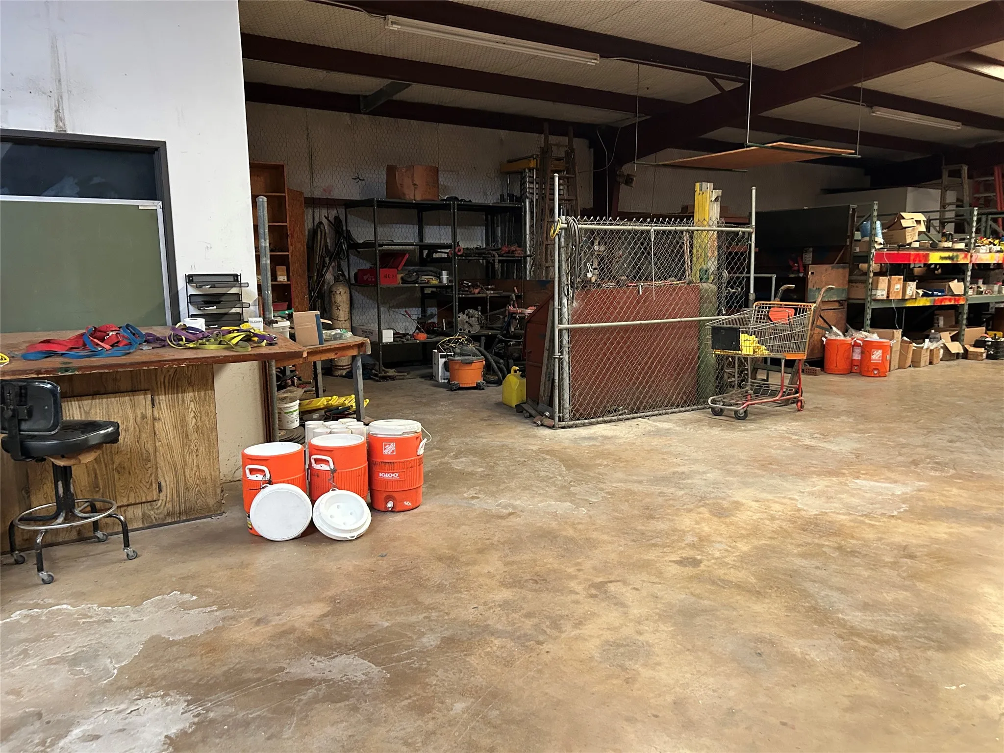 Spacious interior featuring exposed beam ceiling, concrete flooring, and ample room for storage and work areas