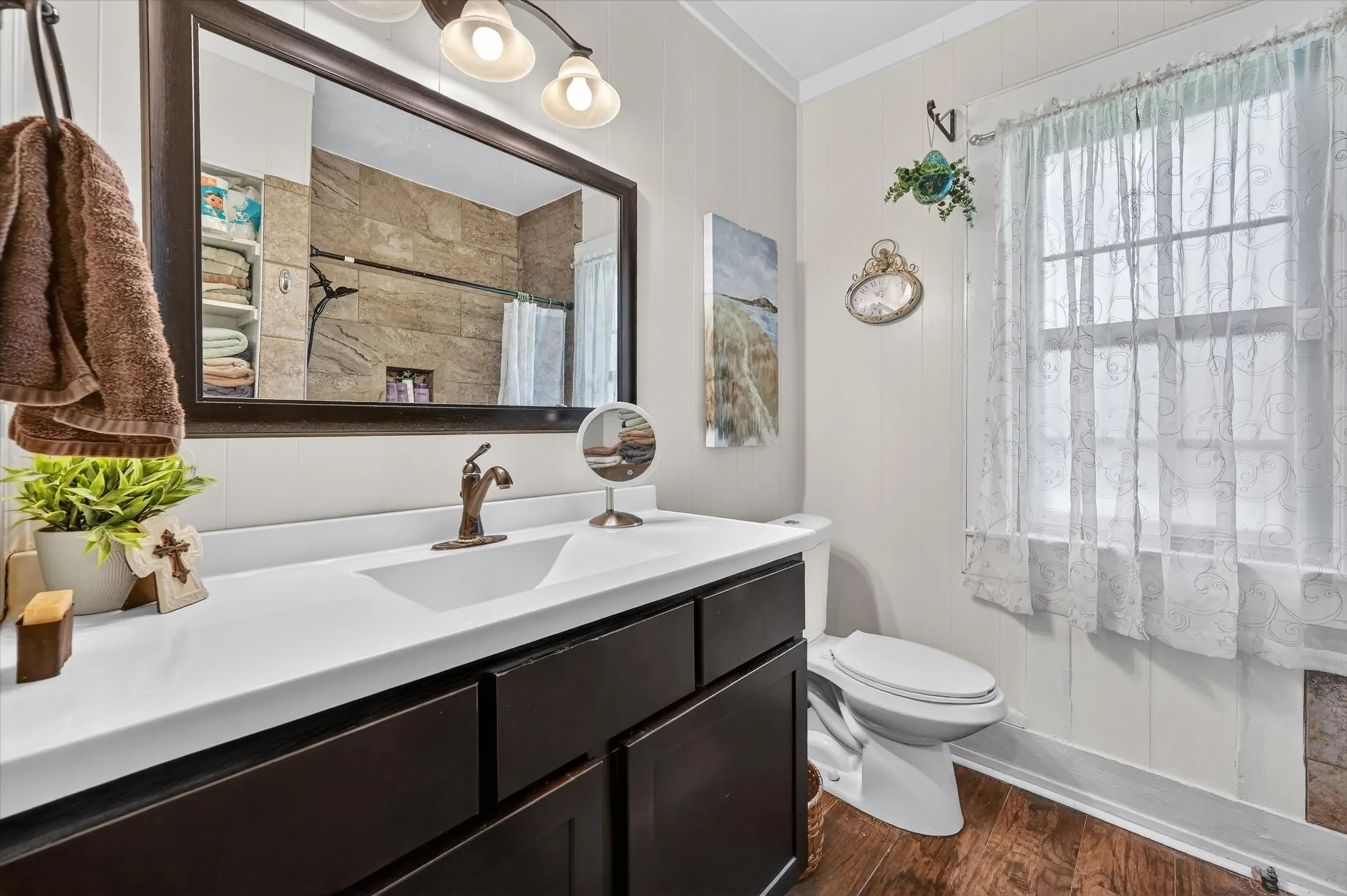 Bathroom featuring a dark wood-finish vanity with an integrated white sink, a bronze-finish faucet, and coordinating wall-mounted mirror