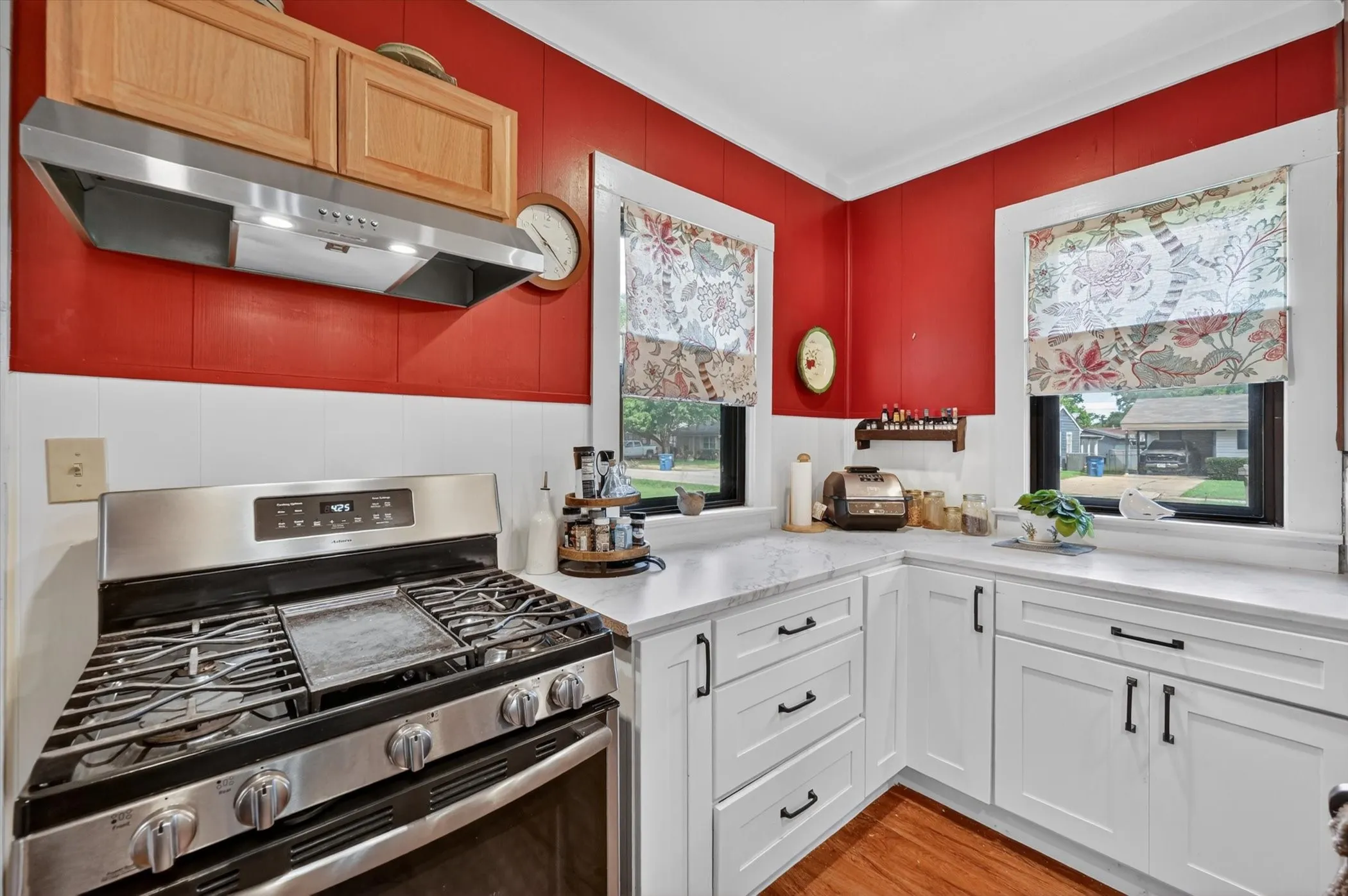 Well-appointed kitchen featuring a stainless steel gas range with overhead ventilation, white shaker cabinetry, and light-toned countertops