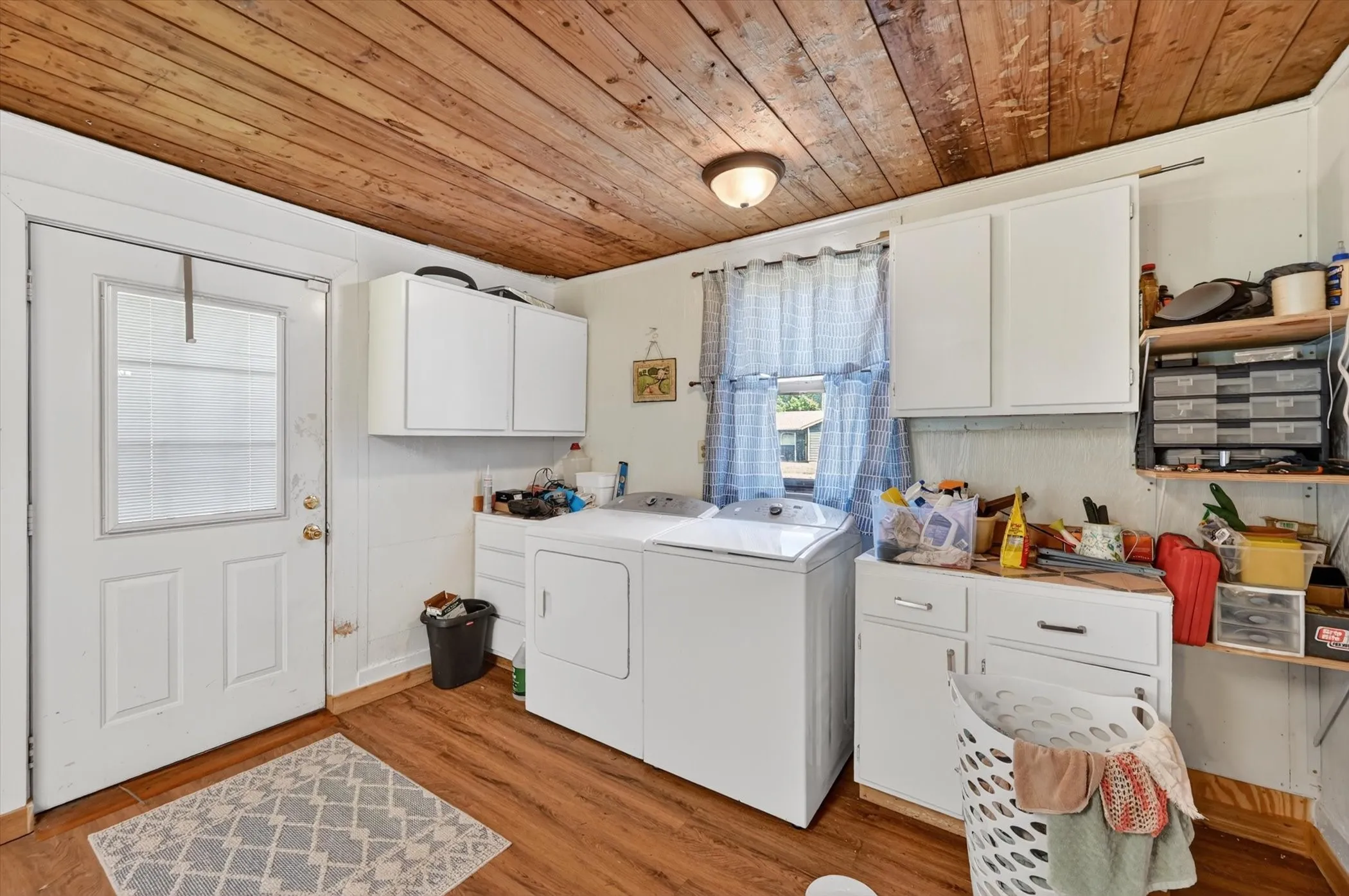 Utility room featuring wood-finish flooring, a paneled wood ceiling, white cabinetry, and built-in shelving