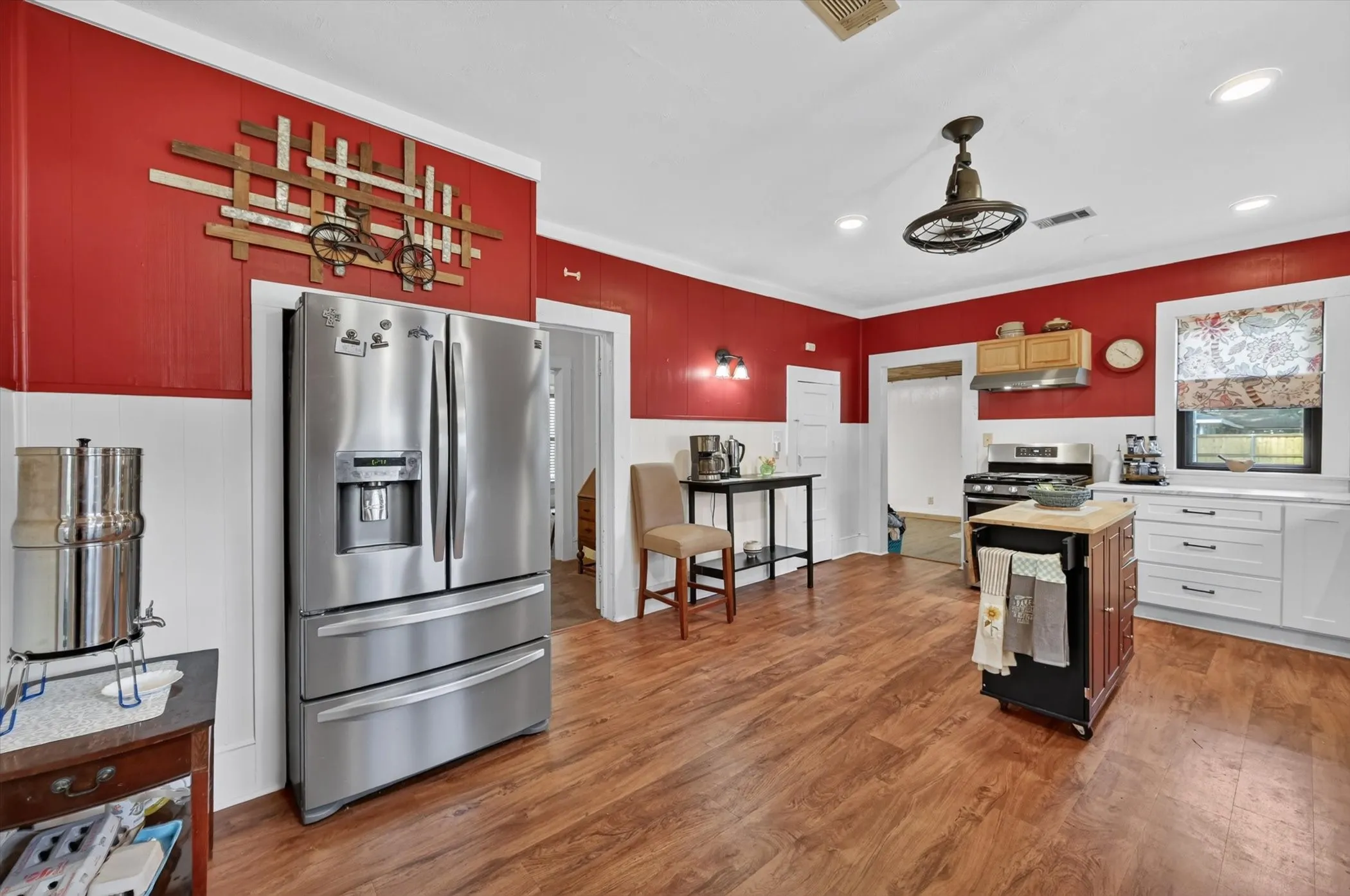 Kitchen featuring wood-finish flooring, white cabinetry, a built-in oven, and a range hood