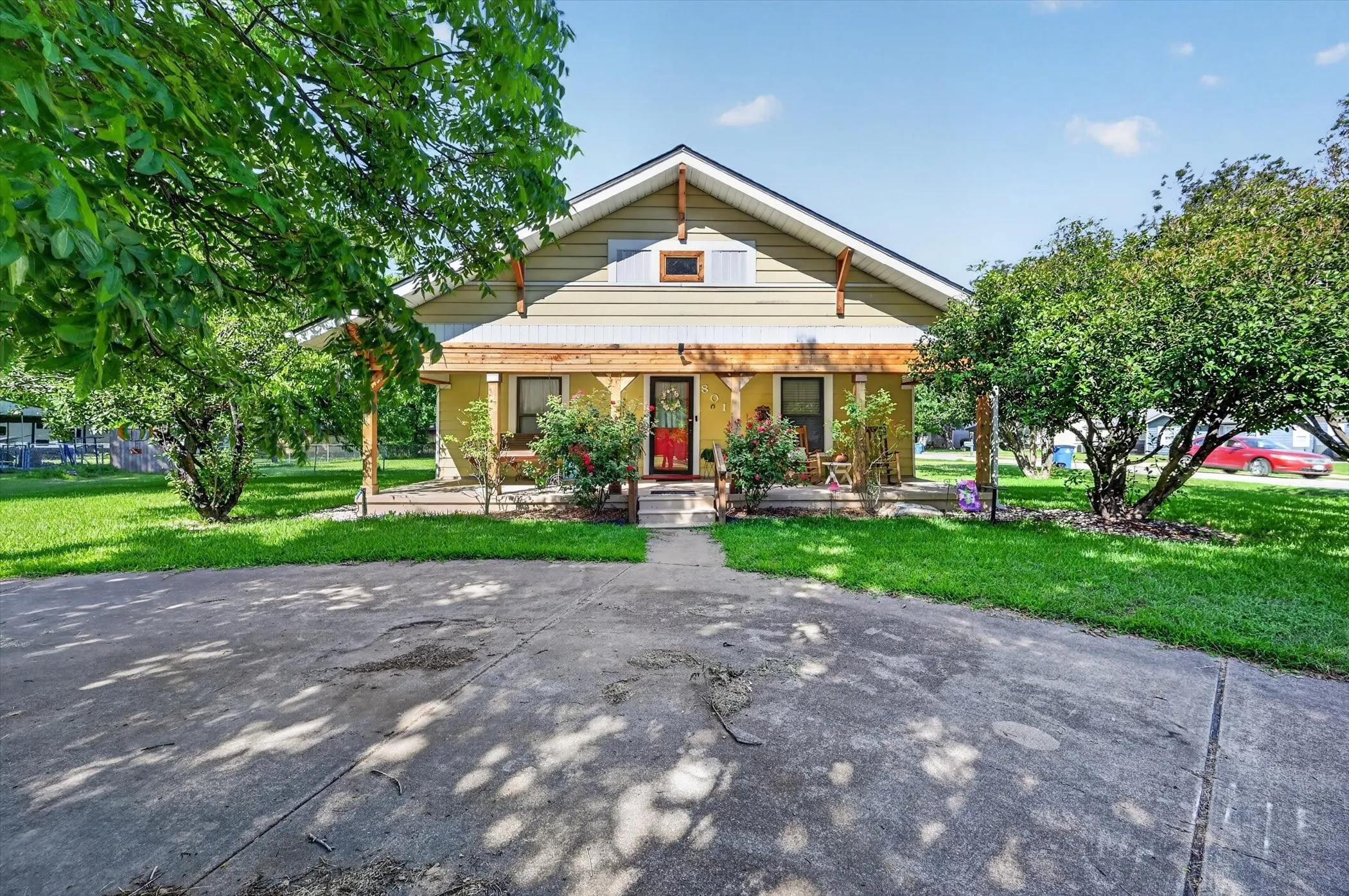 Gable-roof home featuring light yellow siding and a covered front porch with exposed wood beams
