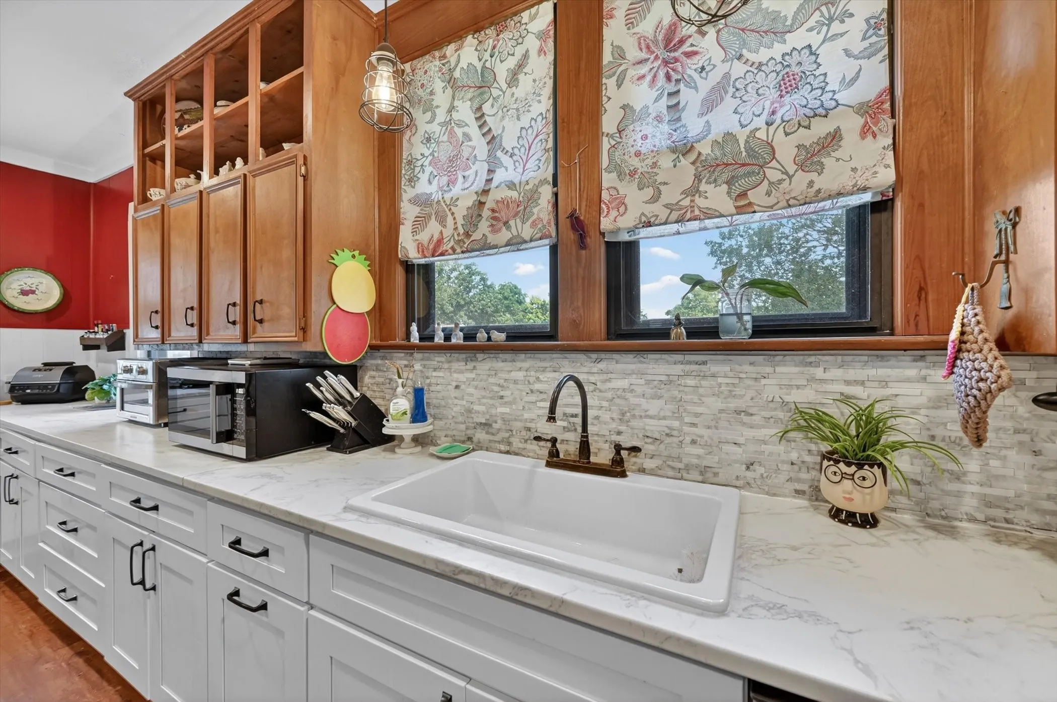 Spacious kitchen featuring white shaker-style base cabinetry with dark hardware, a large undermount sink, and light-toned countertops