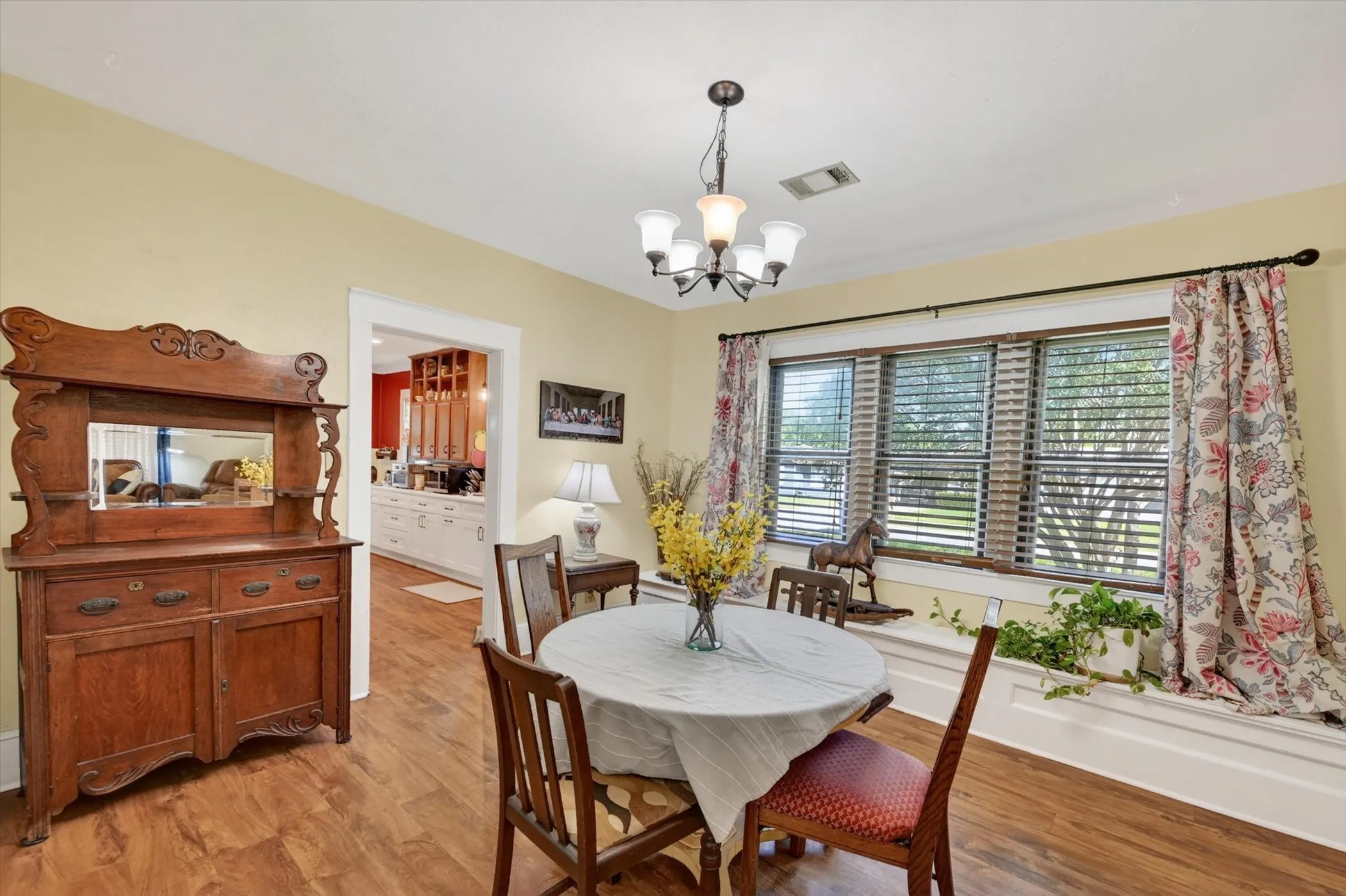 Dining area featuring wood-finish flooring, a multi-pane window with blinds, and a built-in window seat