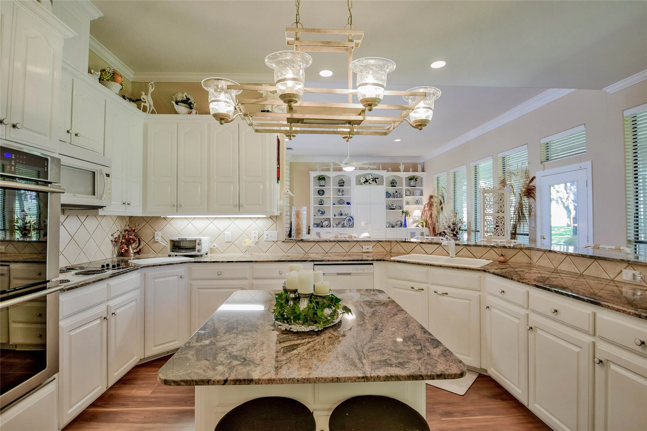 Kitchen with dark stone counters, crown molding, a center island, decorative backsplash, and white appliances