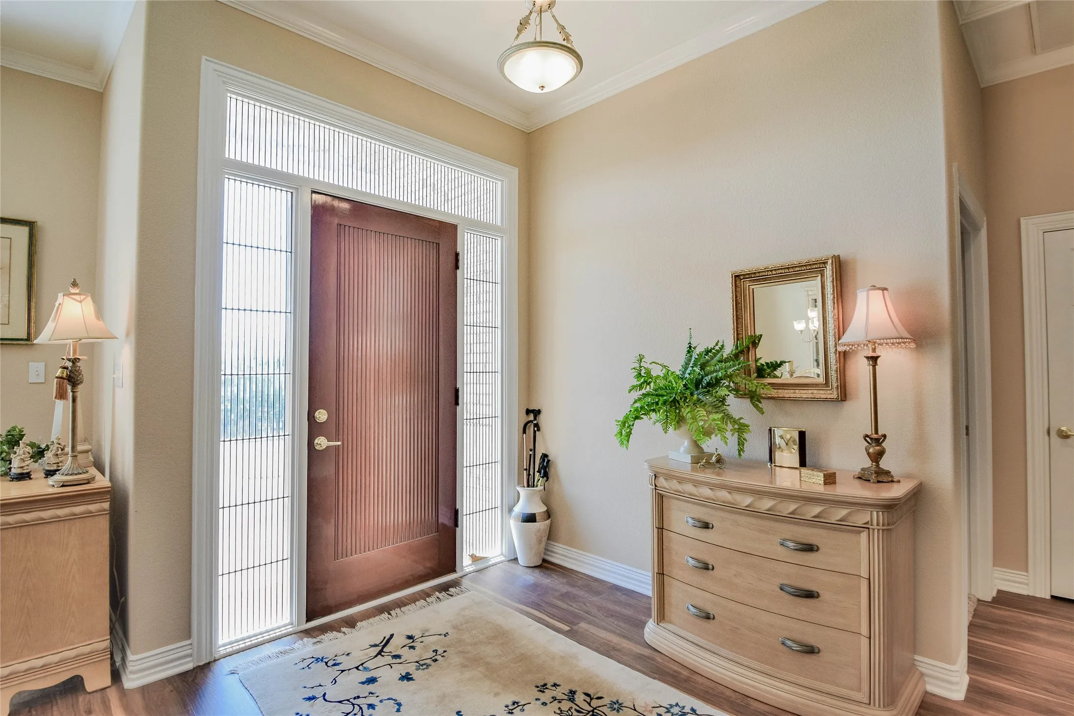 Foyer entrance featuring crown molding and wood finished floors