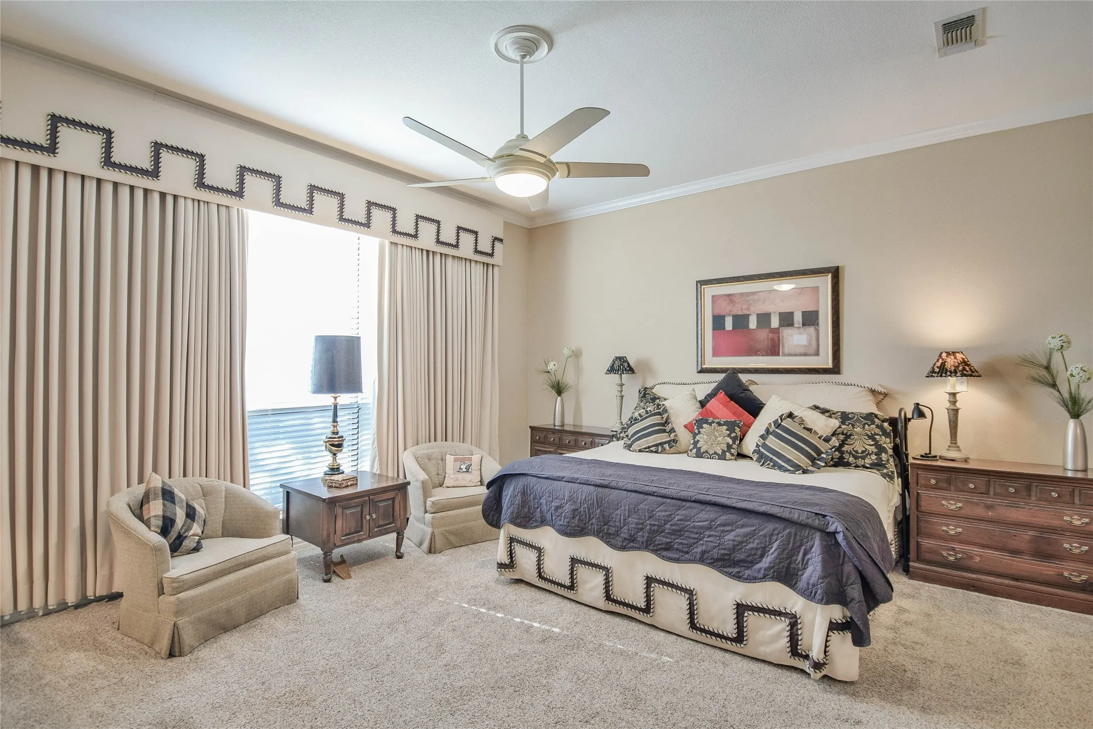 Carpeted bedroom with ornamental molding and a ceiling fan
