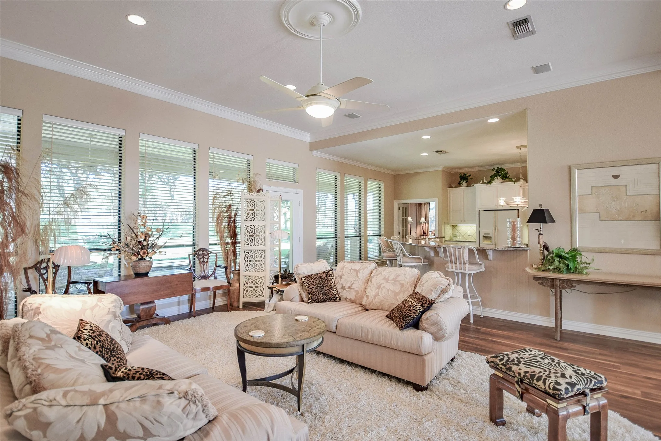 Living area with crown molding, wood finished floors, recessed lighting, and a ceiling fan