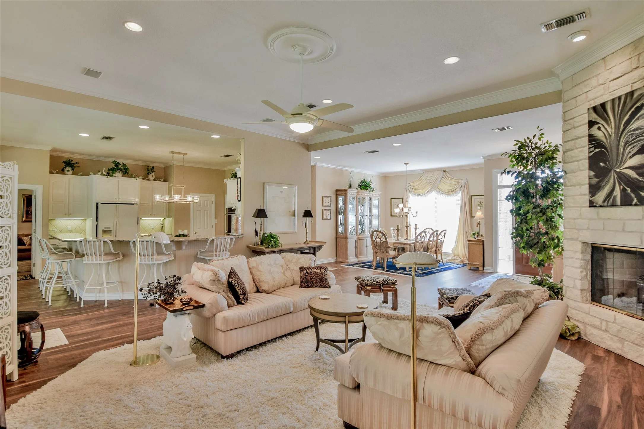 Living room featuring crown molding, a chandelier, a ceiling fan, wood finished floors, and a fireplace