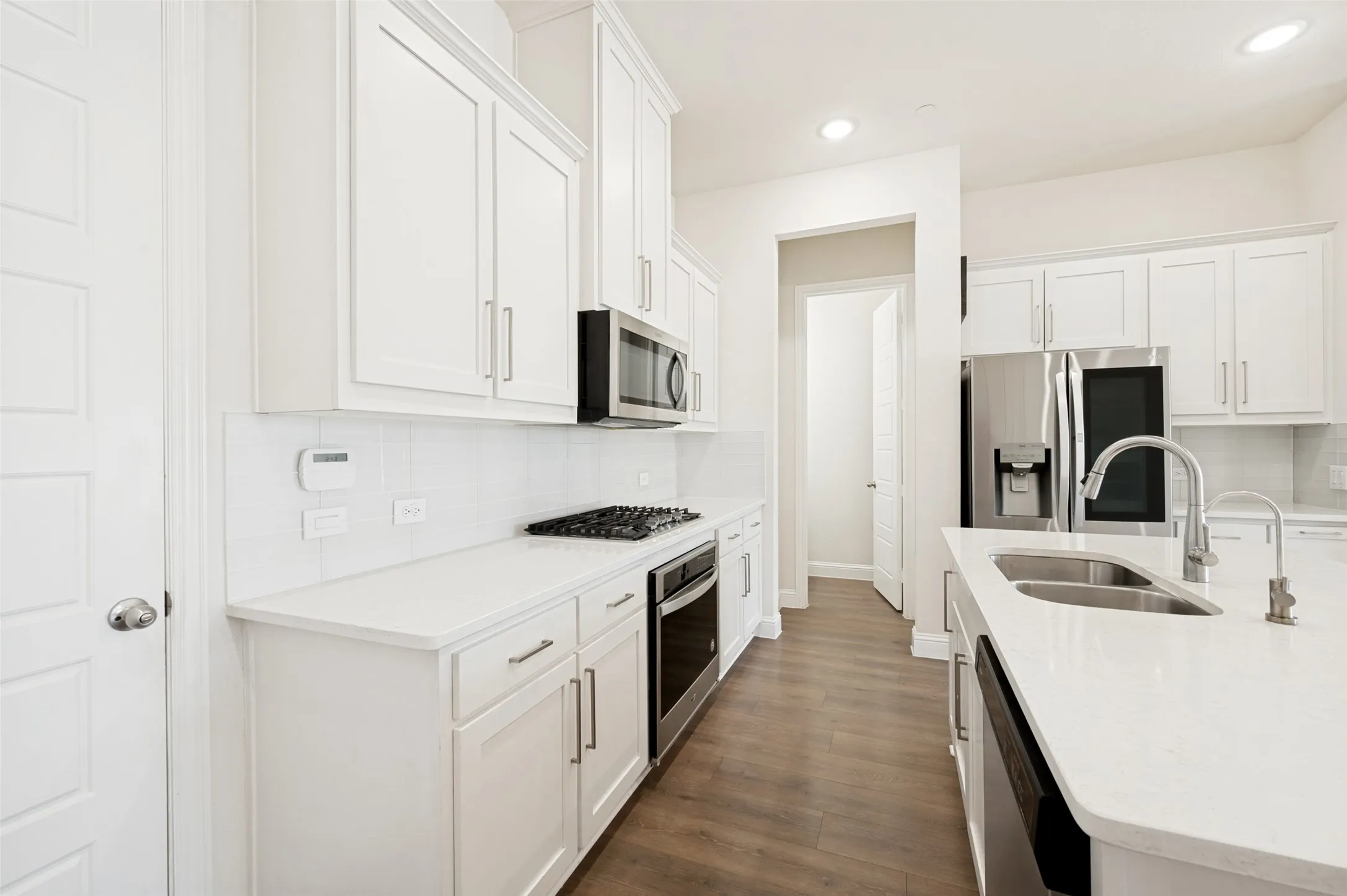Modern kitchen featuring white shaker cabinetry, white subway tile backsplash, stainless steel appliances, and a double basin sink with a gooseneck faucet