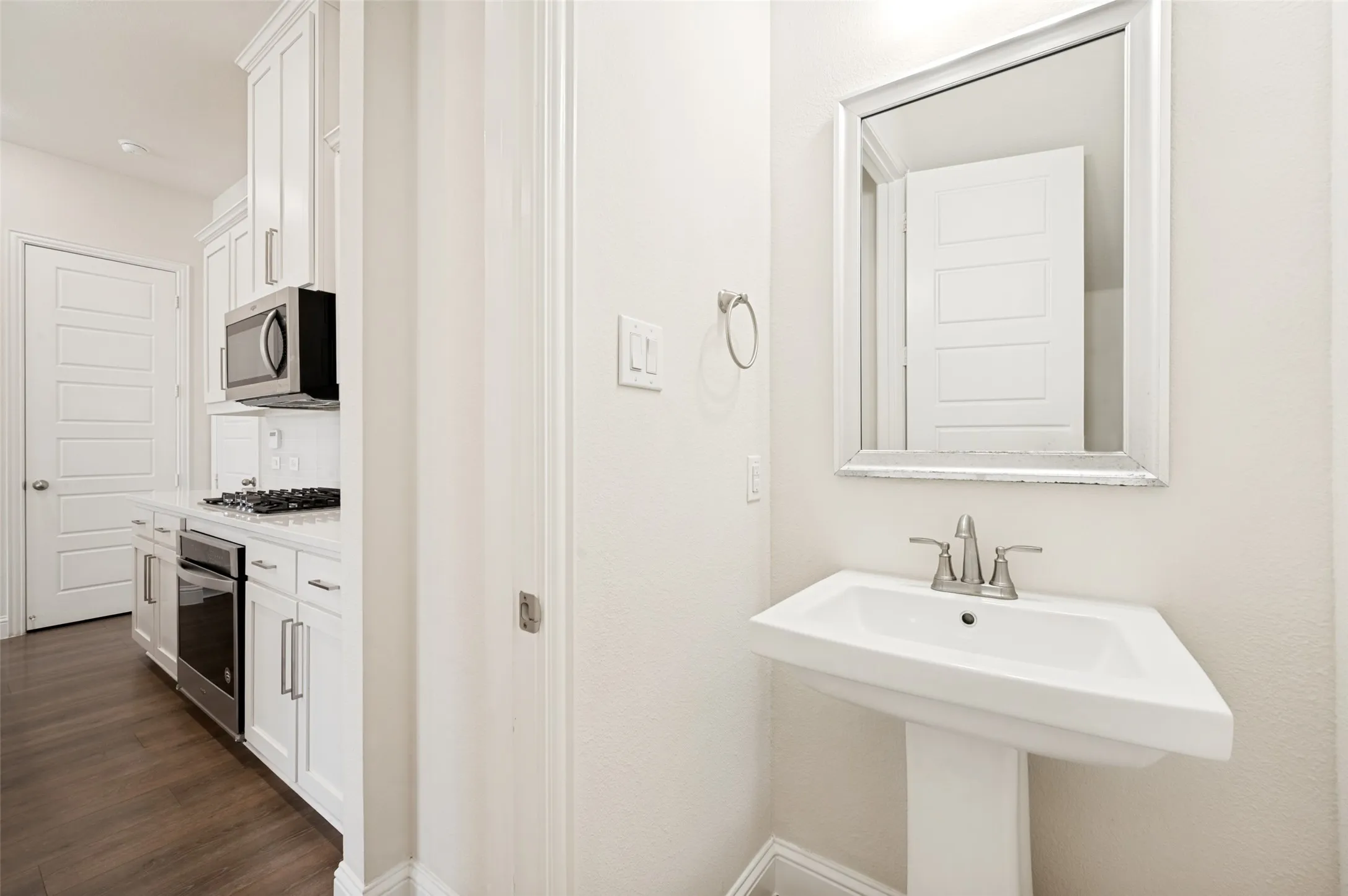 Pedestal sink with a framed mirror and brushed nickel fixtures