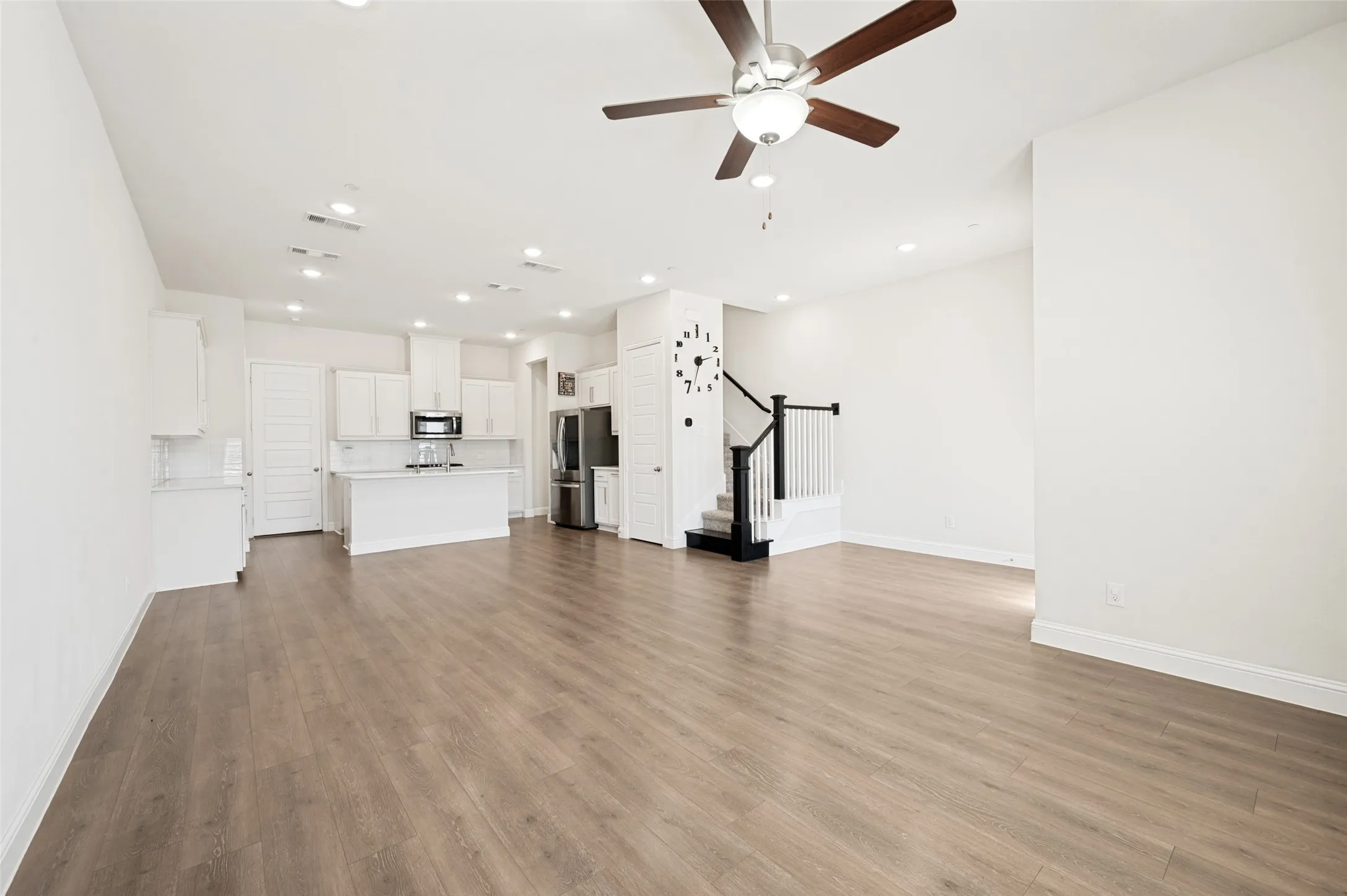 Open-concept living space featuring wood-finish flooring, recessed lighting, and a ceiling fan