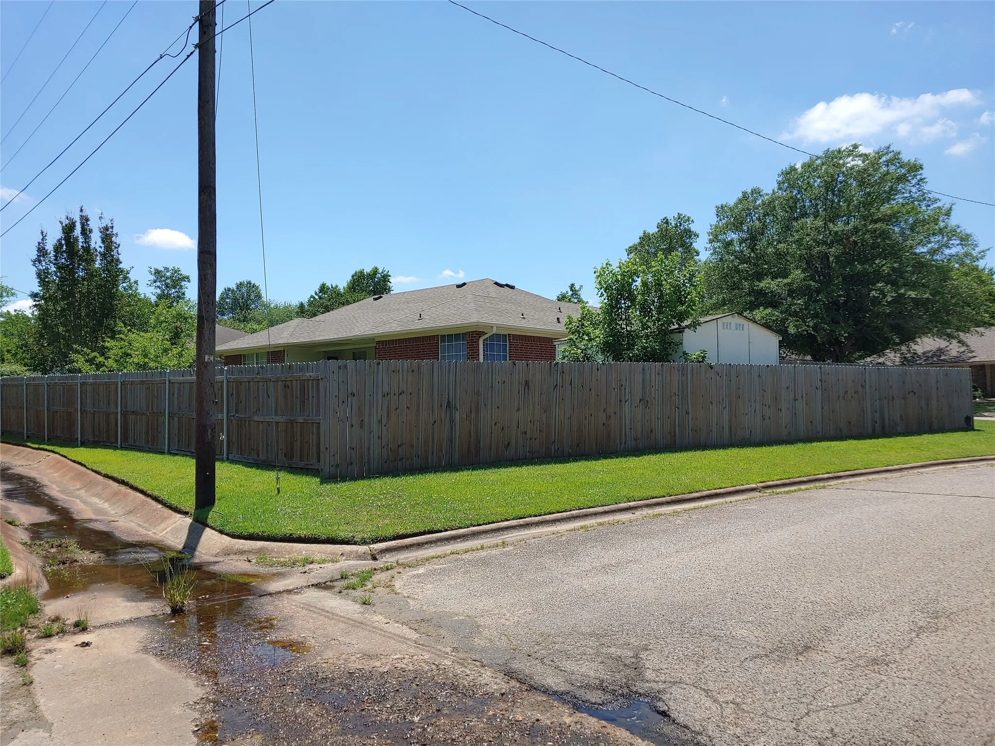 Corner lot with wood privacy fencing, mature trees, and a well-maintained lawn