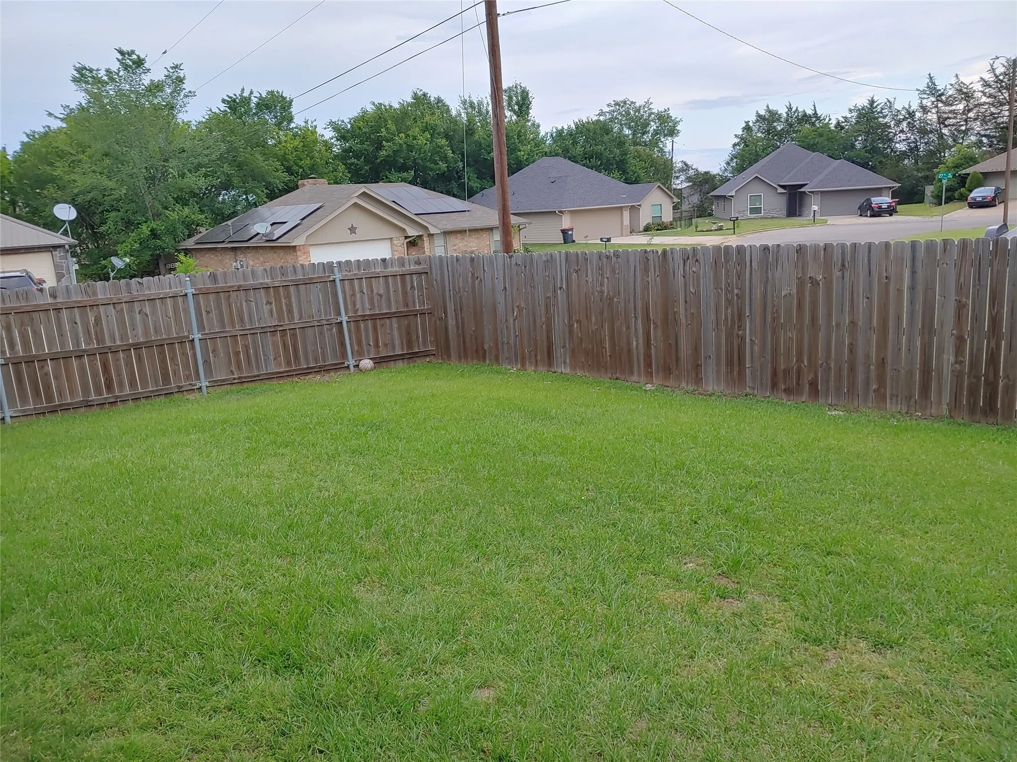 Expansive backyard featuring a lush green lawn, full wood privacy fencing, and mature perimeter trees