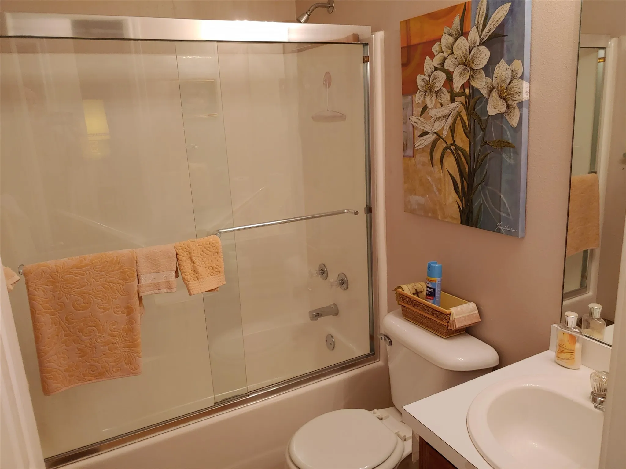 Full bathroom featuring a shower-tub combination with sliding glass doors, a single vanity with an integrated sink, and a commode