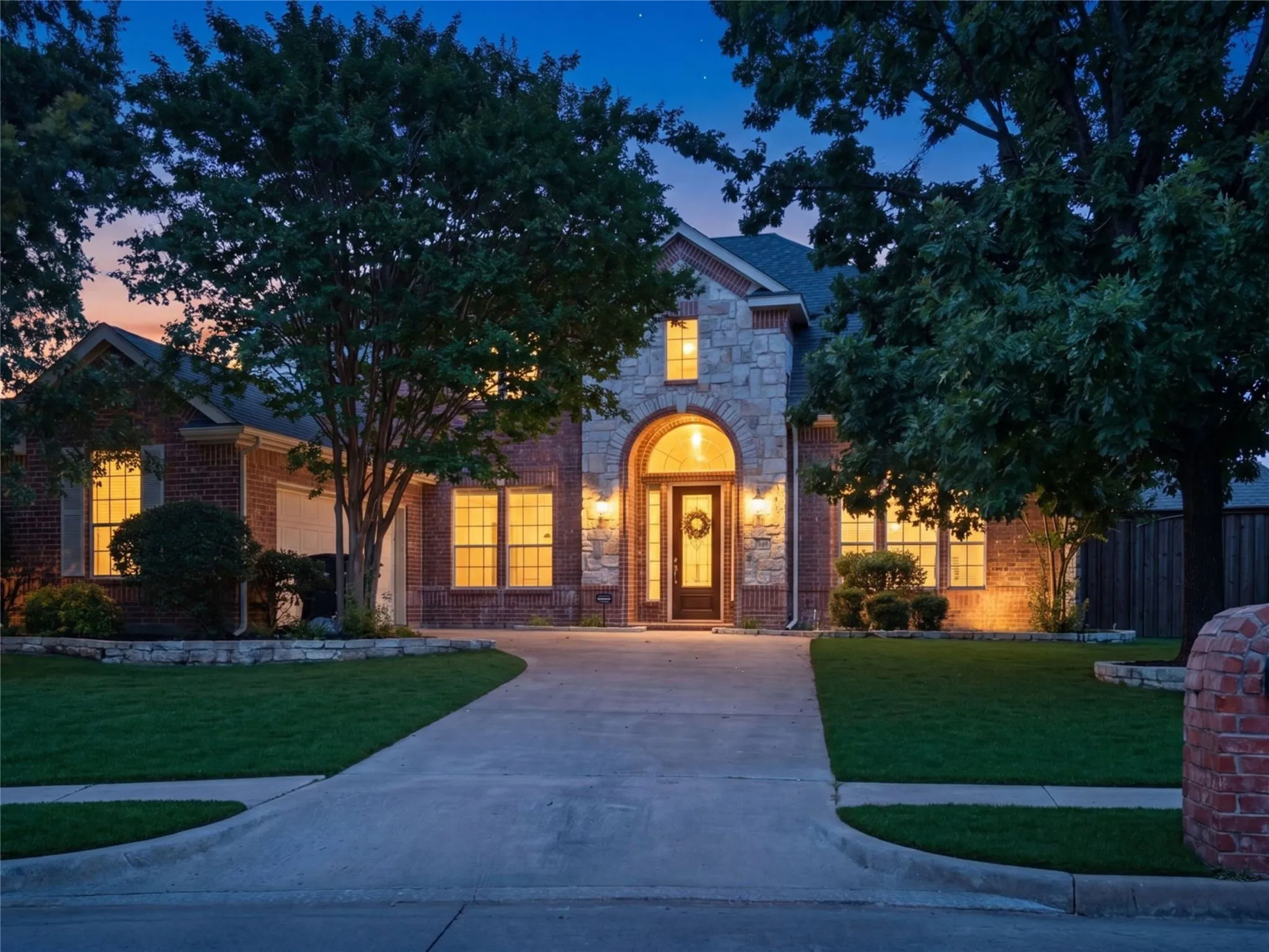As evening falls, warm architectural lighting and timeless curb appeal create a welcoming arrival that feels equally elegant day or night.