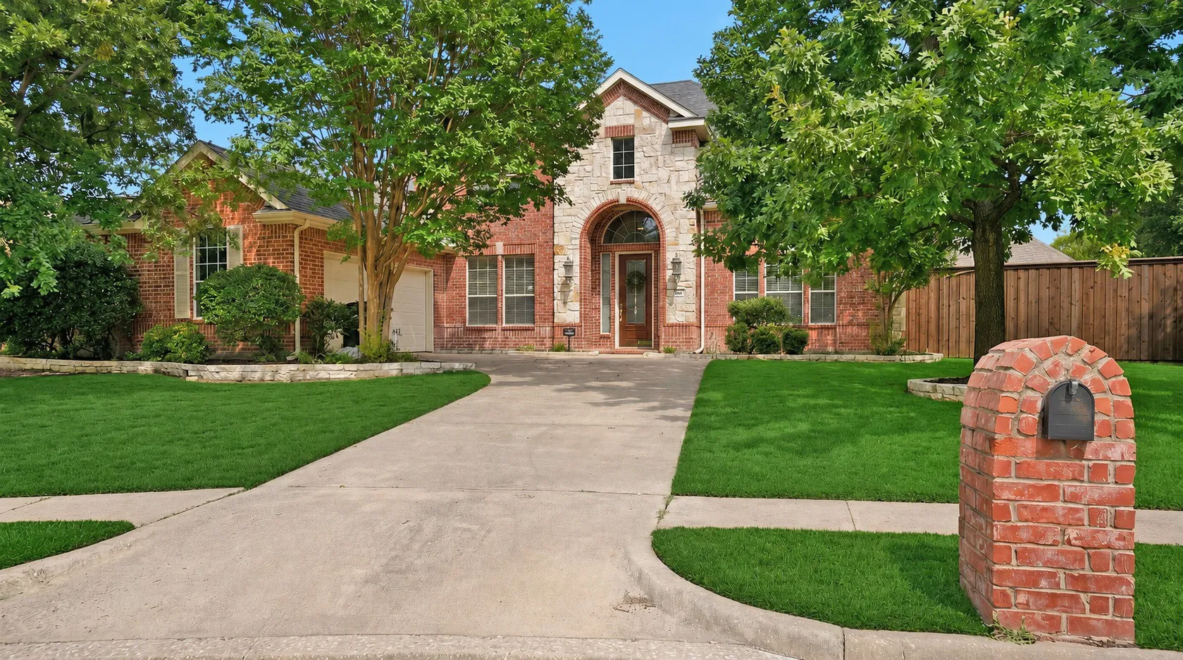 Timeless curb appeal begins with an elegant brick and stone façade, mature shade trees, and a dramatic arched entry that creates a memorable first impression before you ever step inside.