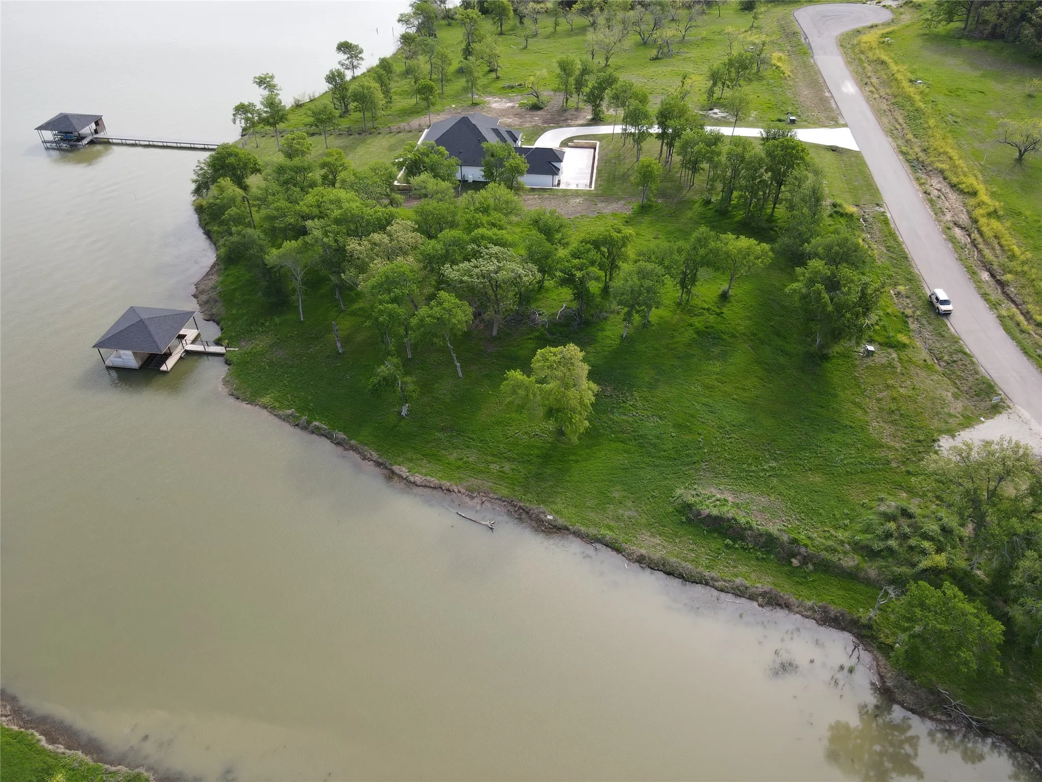 Aerial shoreline angle highlights the private waterfront feel, natural trees, and open lake access.