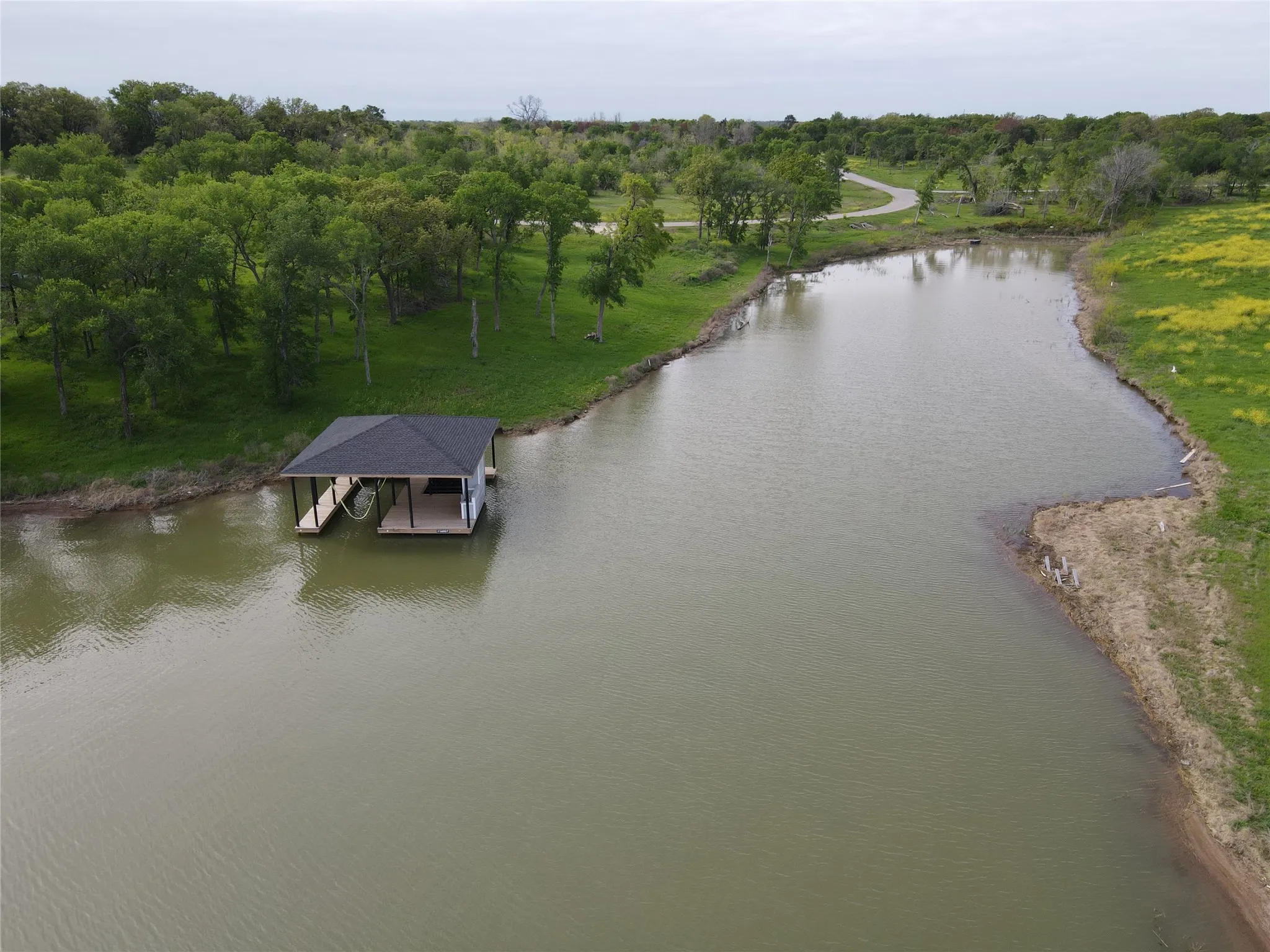 Aerial lakefront perspective captures the boathouse, gentle bank, and spacious waterfront setting.