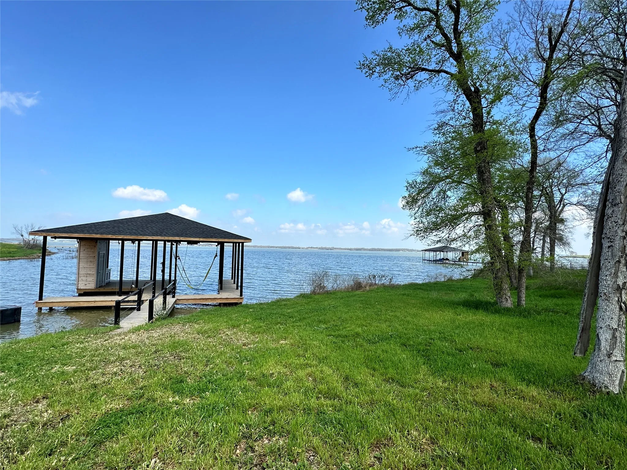 Boathouse view from the lawn showcases the lifestyle buyers want: boating, fishing, and relaxing by the water.
