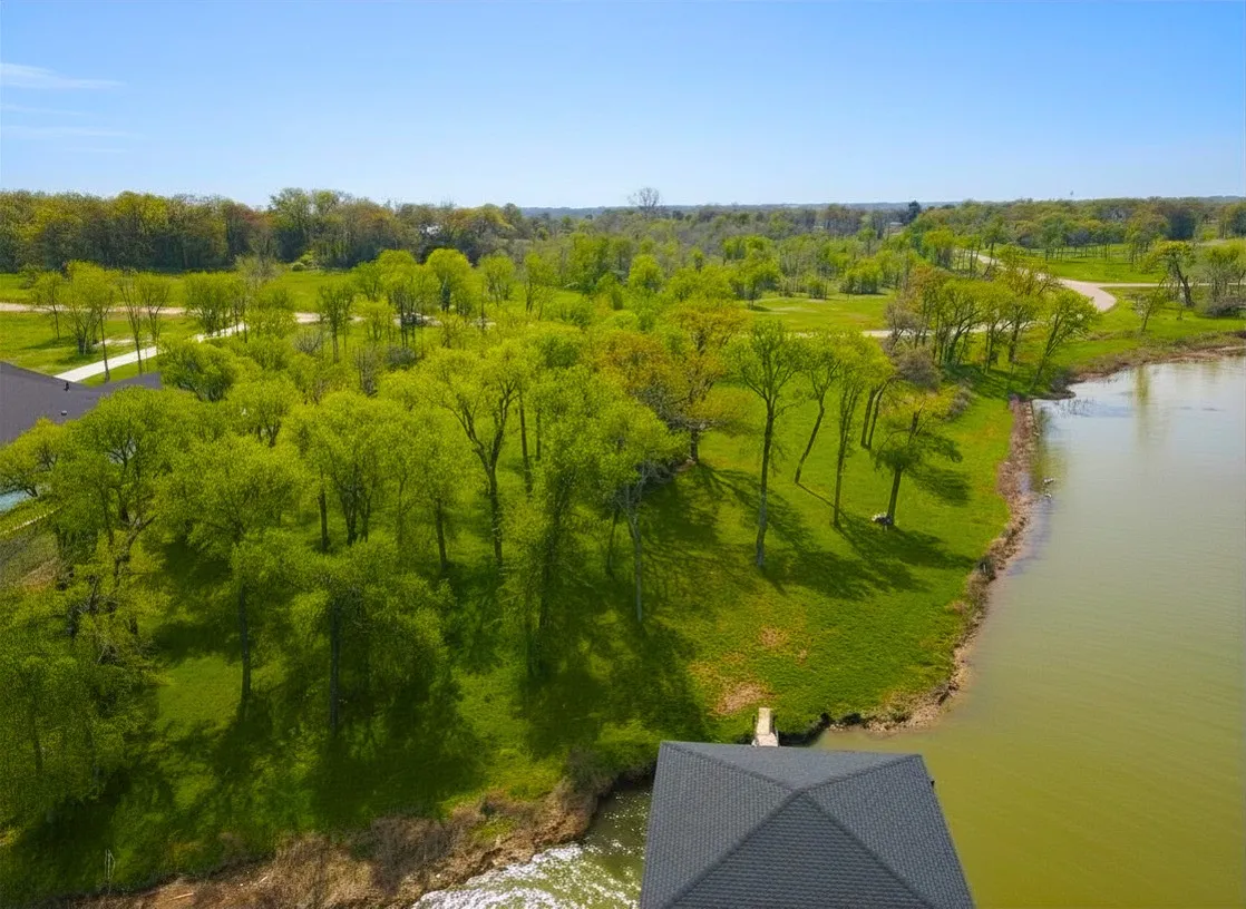 Aerial view shows the treed shoreline, gentle slope, and spacious build potential on this Diamond Point lakefront lot.
