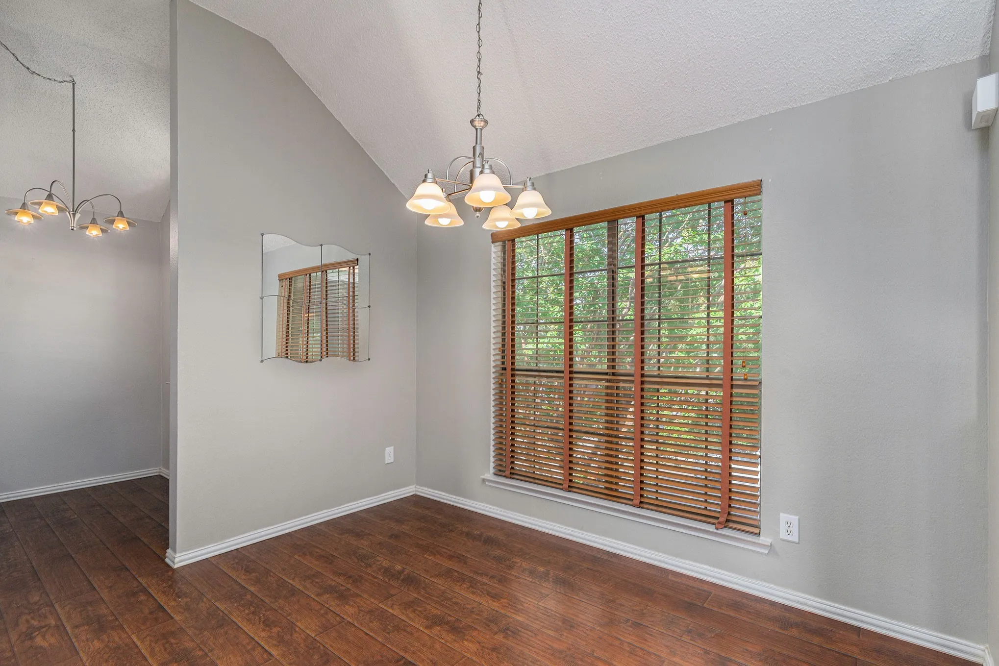 Unfurnished dining area with dark wood-type flooring, a notable chandelier, baseboards, and vaulted ceiling