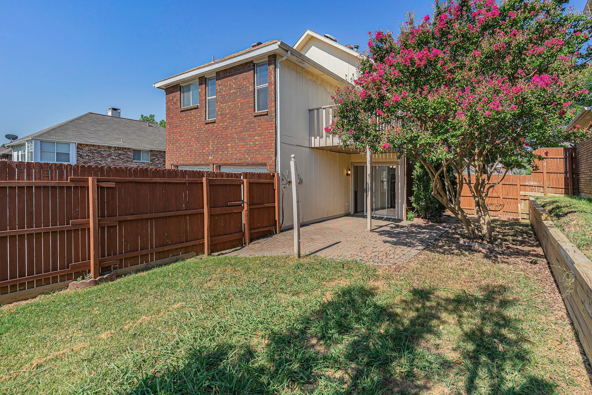 Rear view of property with a yard, a fenced backyard, brick siding, and a patio area