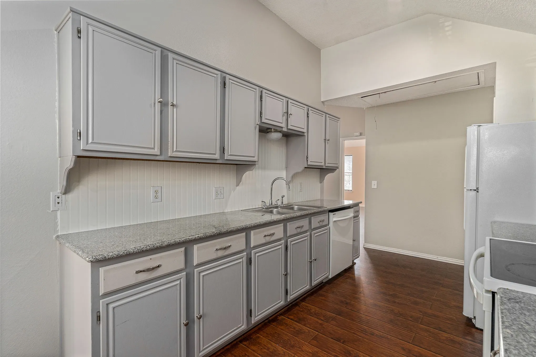 Kitchen with a sink, gray cabinetry, dishwasher, and dark wood finished floors