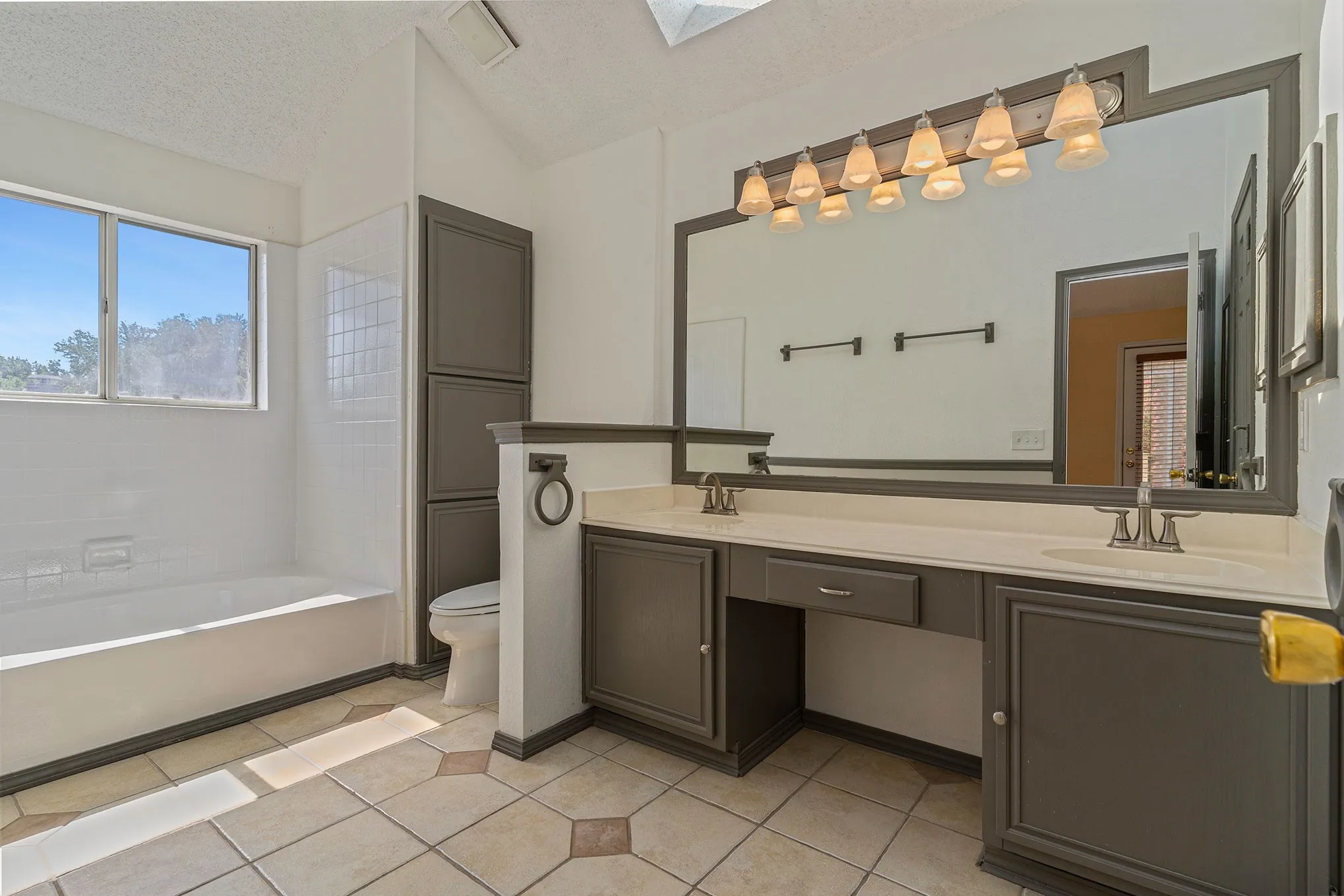 Full bath featuring tile patterned flooring, a sink, toilet, and lofted ceiling