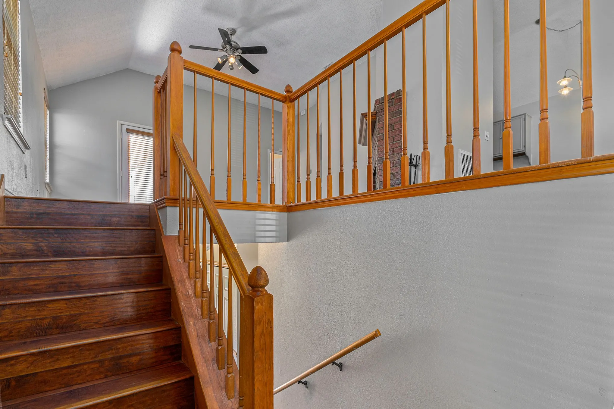 Stairs featuring vaulted ceiling and a ceiling fan