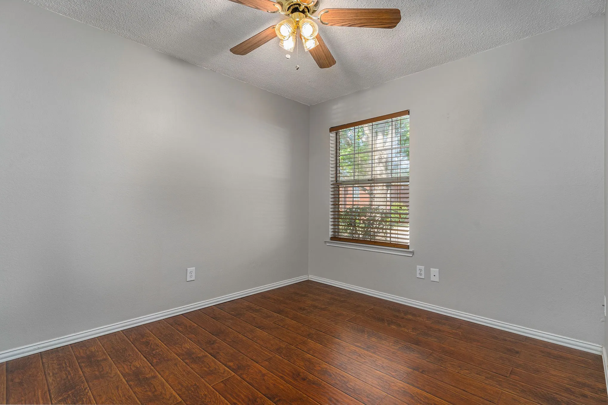 Empty room featuring a ceiling fan, baseboards, a textured ceiling, and dark wood finished floors
