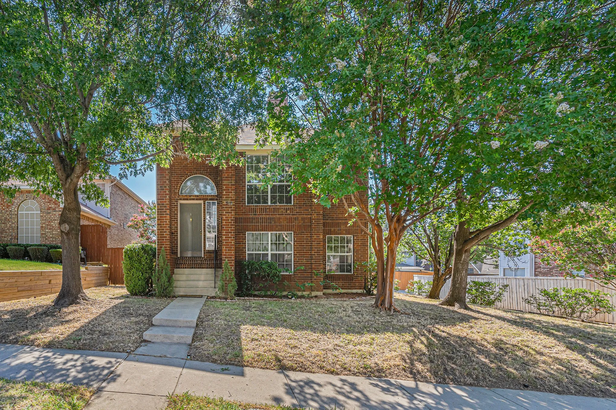 Traditional home with fence and brick siding
