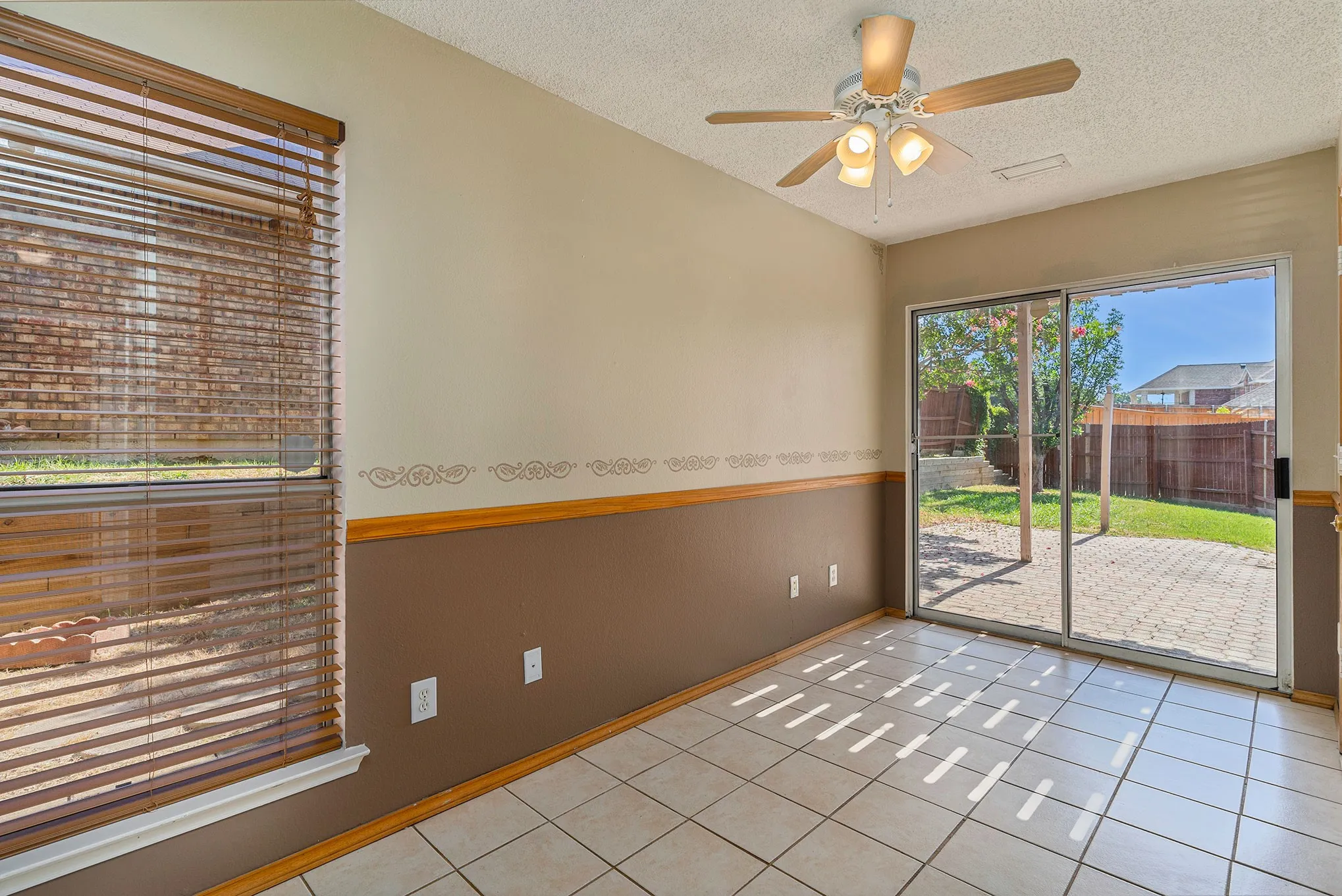 Spare room featuring baseboards, a textured ceiling, a ceiling fan, and light tile patterned flooring