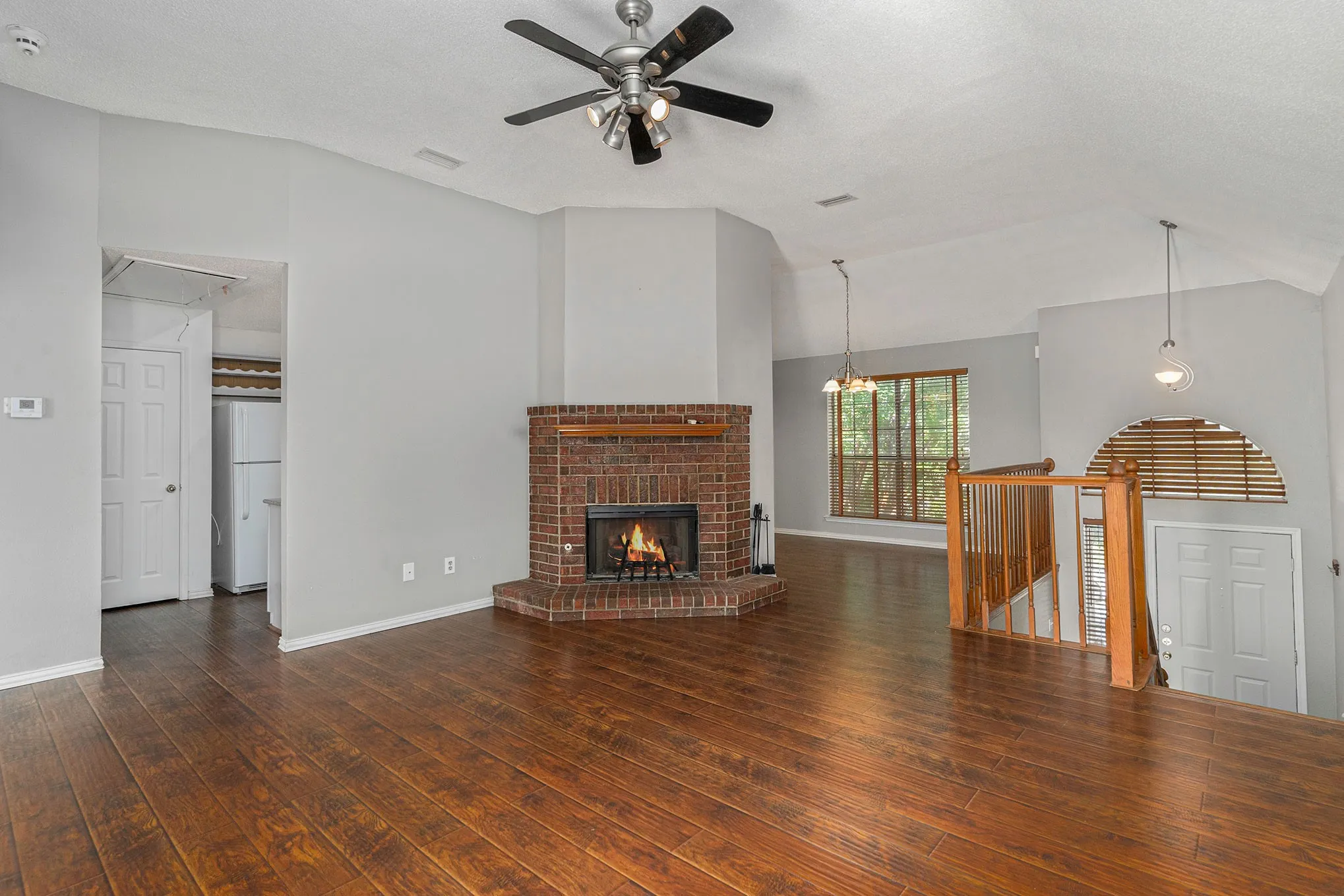 Unfurnished living room with attic access, a ceiling fan, visible vents, lofted ceiling, and wood-type flooring