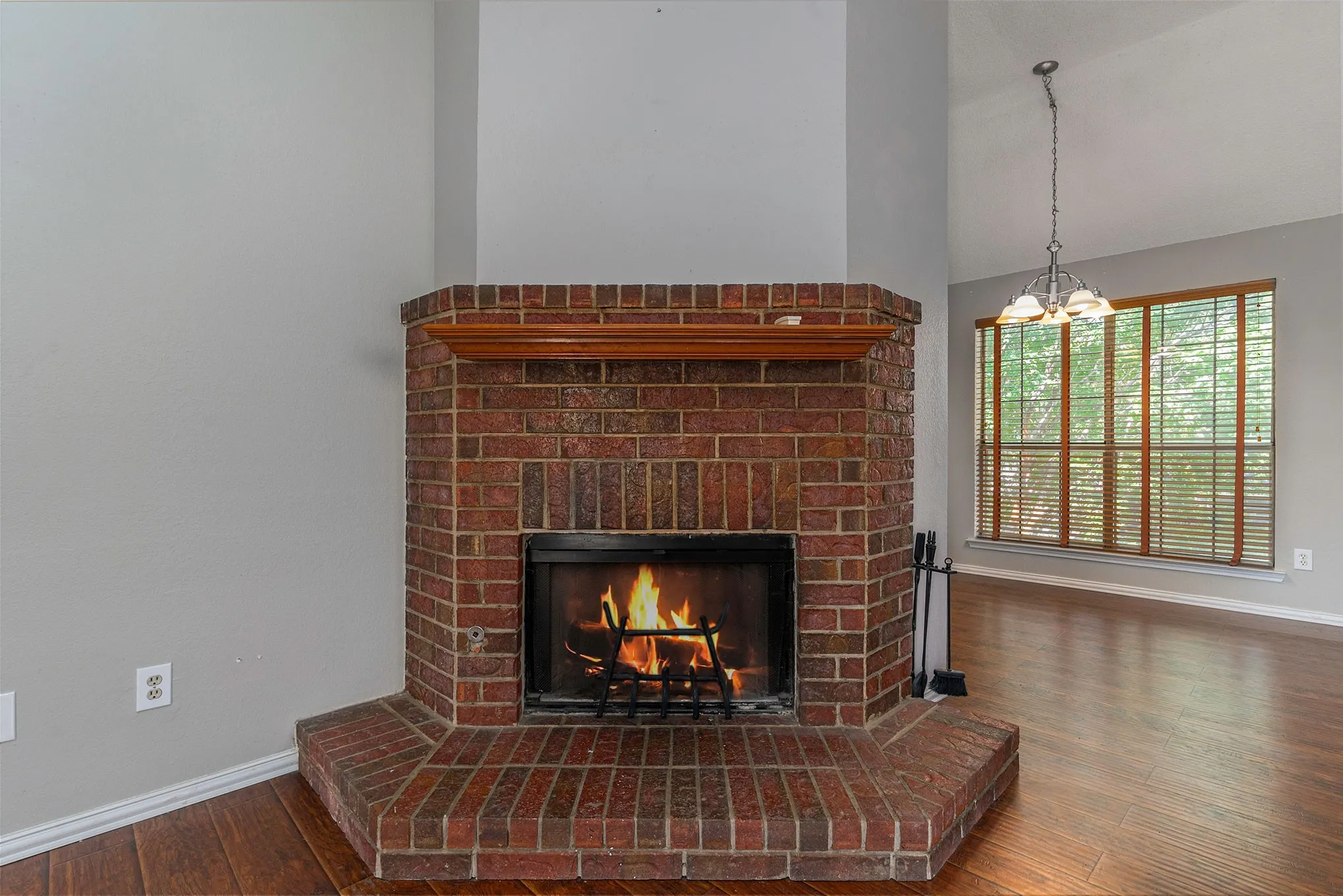 Room details with wood finished floors, a fireplace, baseboards, and a notable chandelier