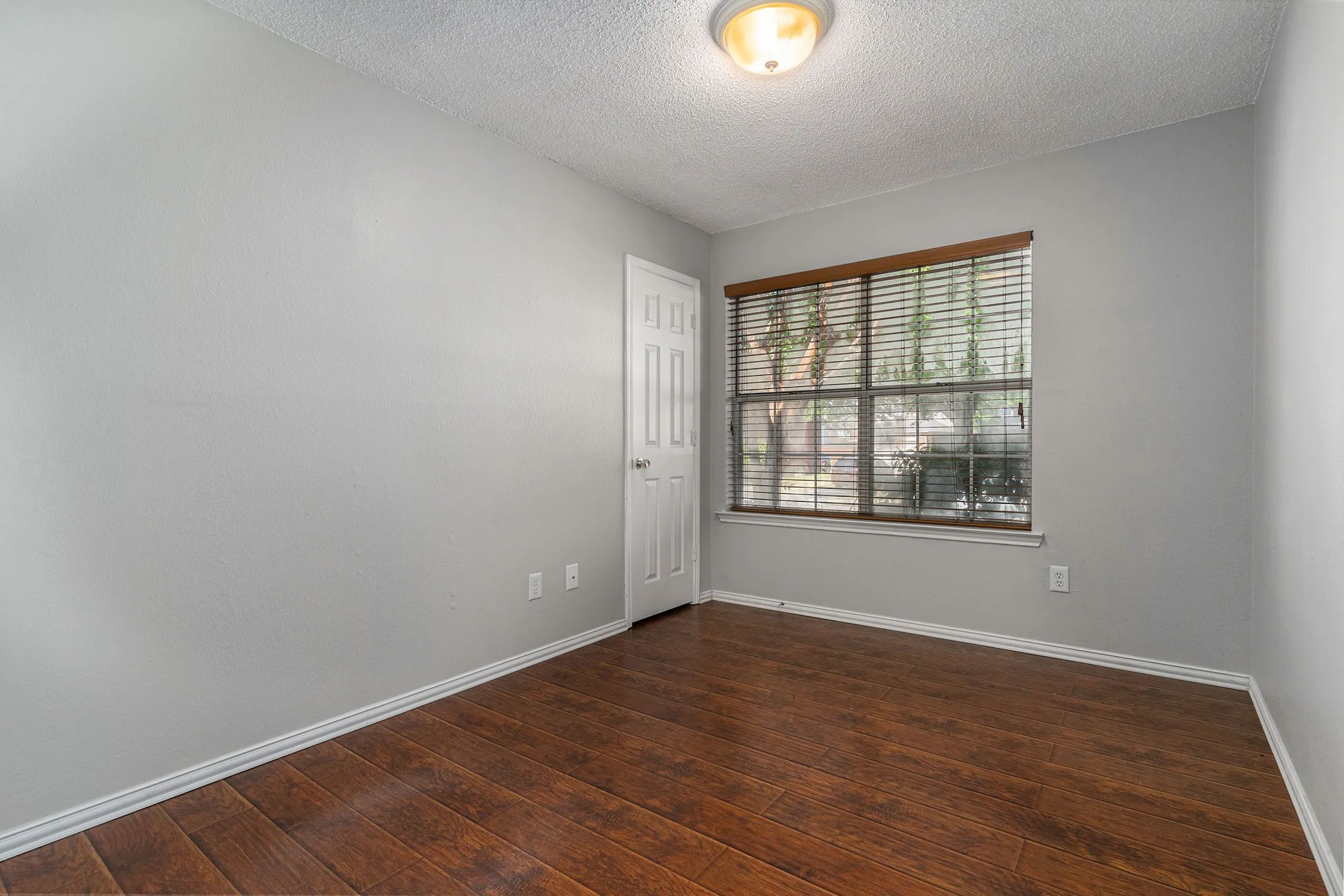 Spare room with hardwood / wood-style floors, a textured ceiling, and baseboards