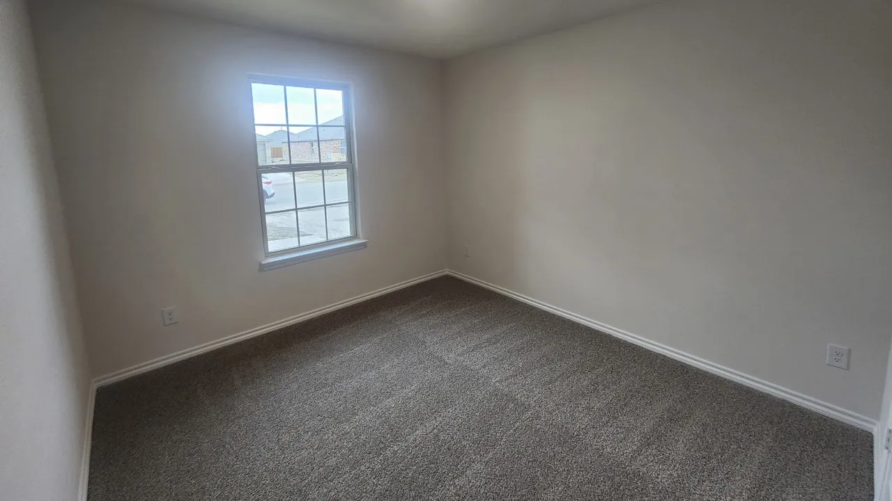 Spacious room featuring neutral paint, gray carpet, white baseboards, and a double-paned window with grid inserts