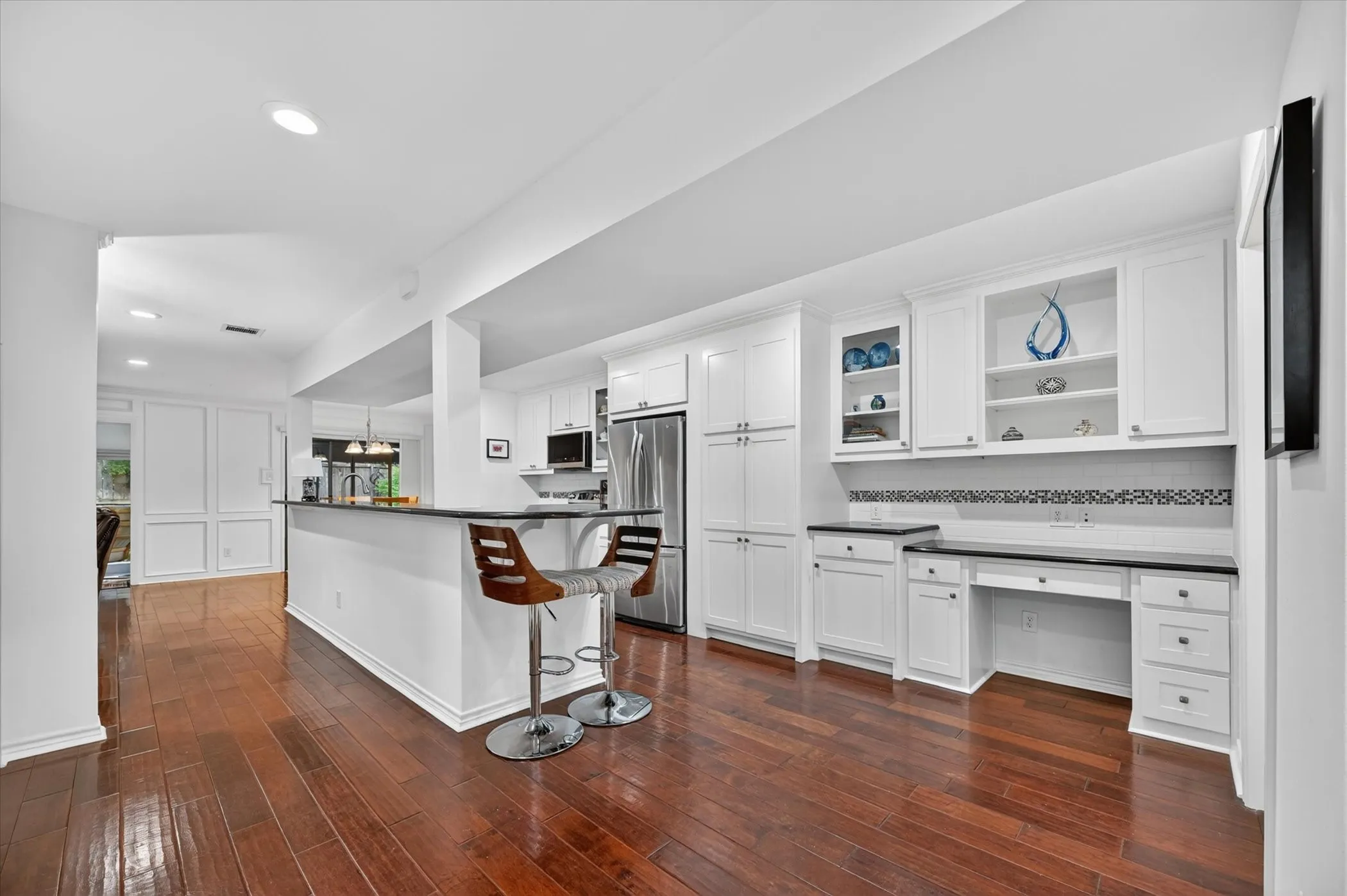 Spacious room featuring rich wood-finish flooring and extensive built-in shelving with recessed lighting.
The room is Virtually staged