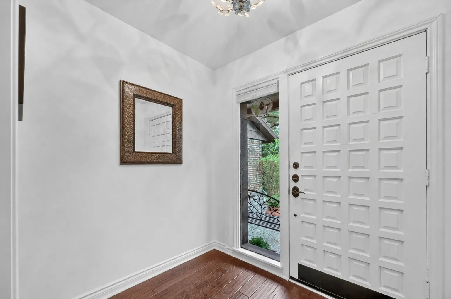 Paneled front entry door with a sidelight, wood-finish flooring, and crown molding